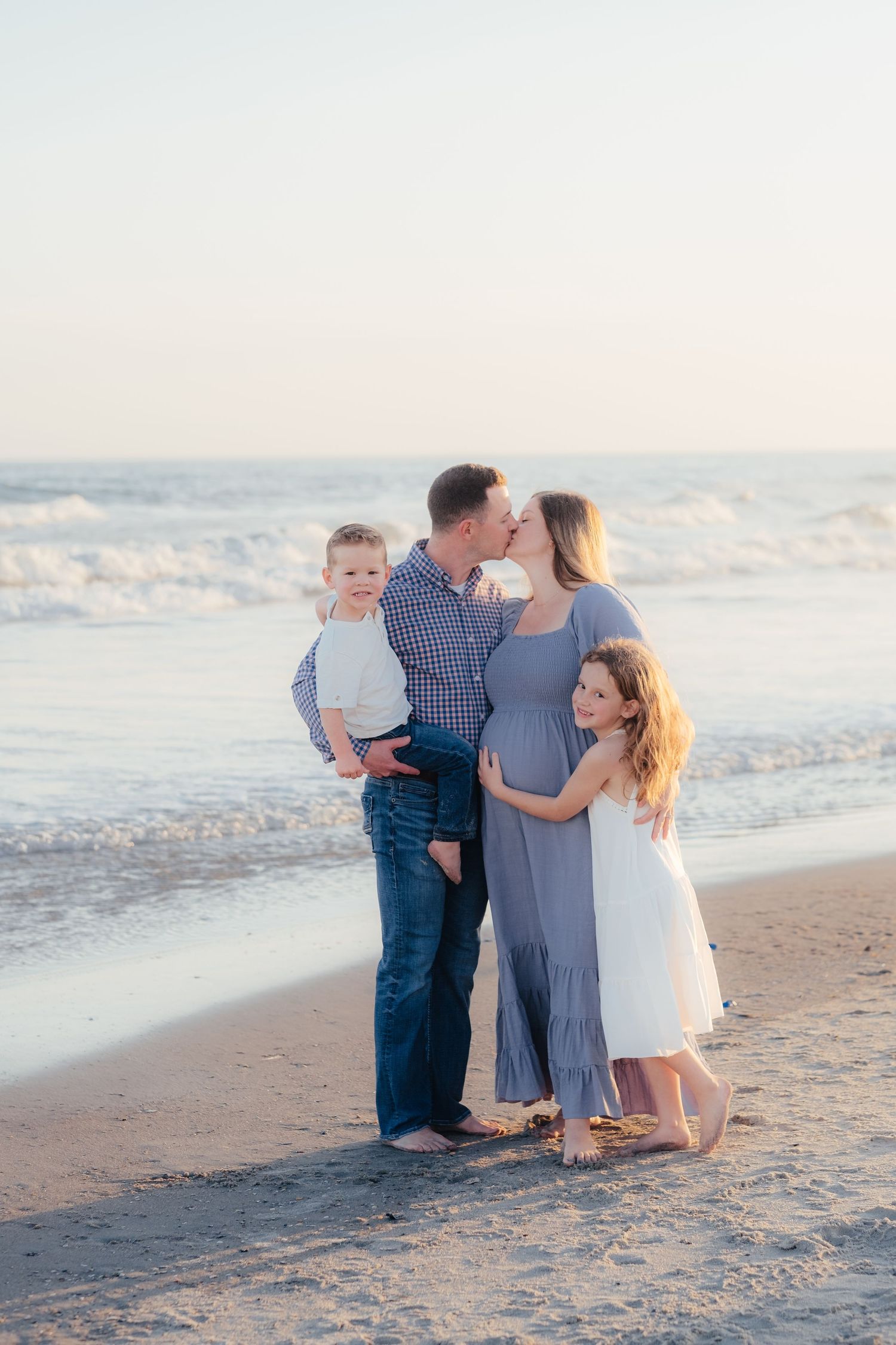 Family enjoying sunset moments together on sandy beach.