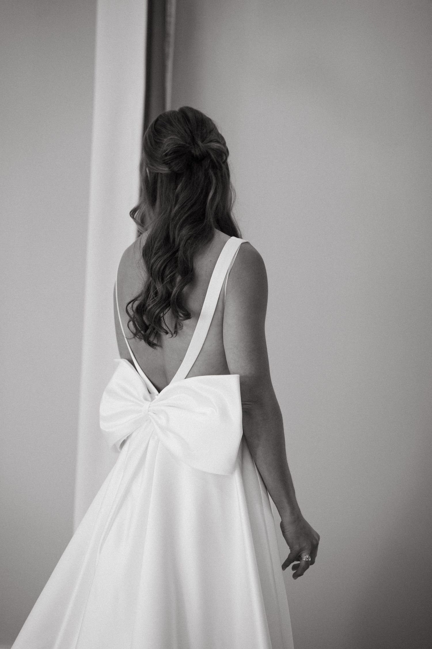 A series of black and white photos showing the back of a white dress with a bow detail against a light background.