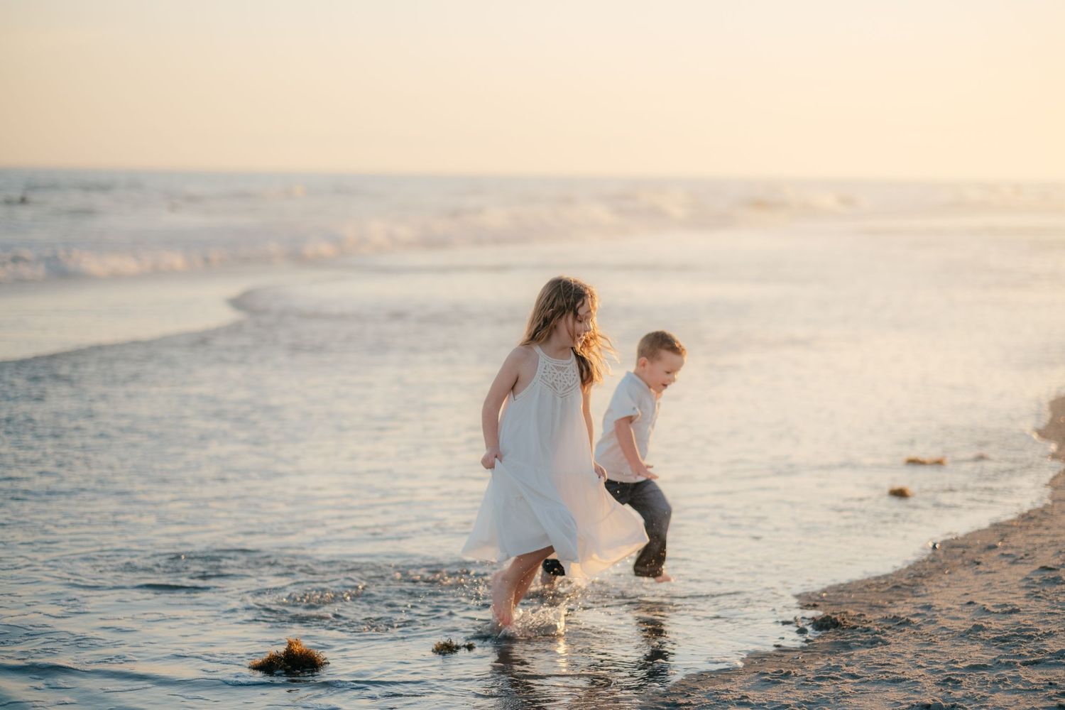 Intimate family moment captured on sandy beach during golden hour.