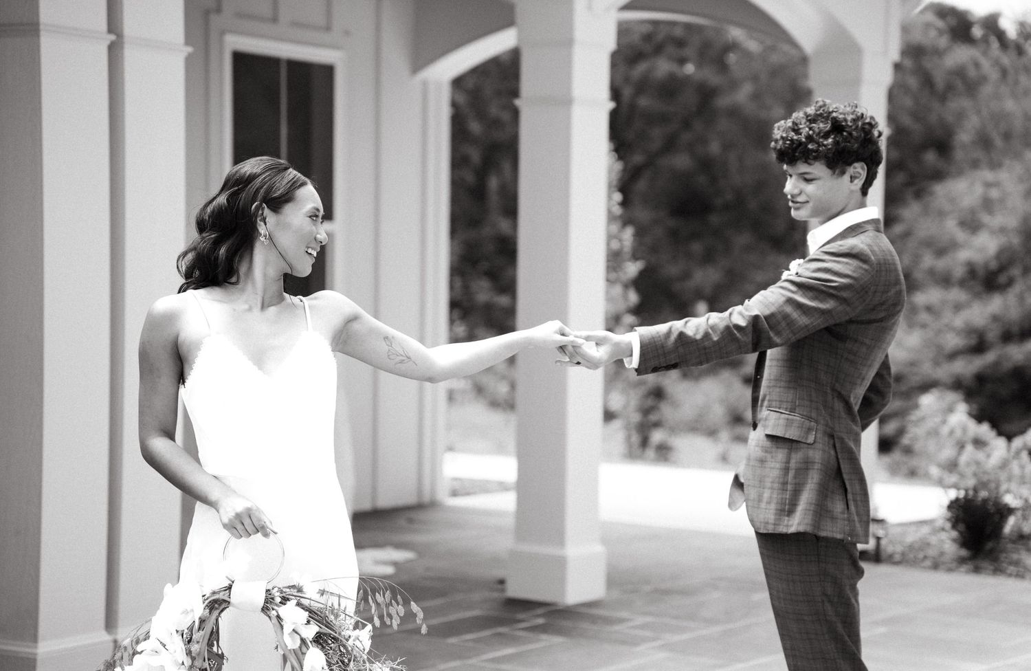 Black and white panoramic wedding photo sequence showing couple dancing under white pillars in elegant outdoor setting.