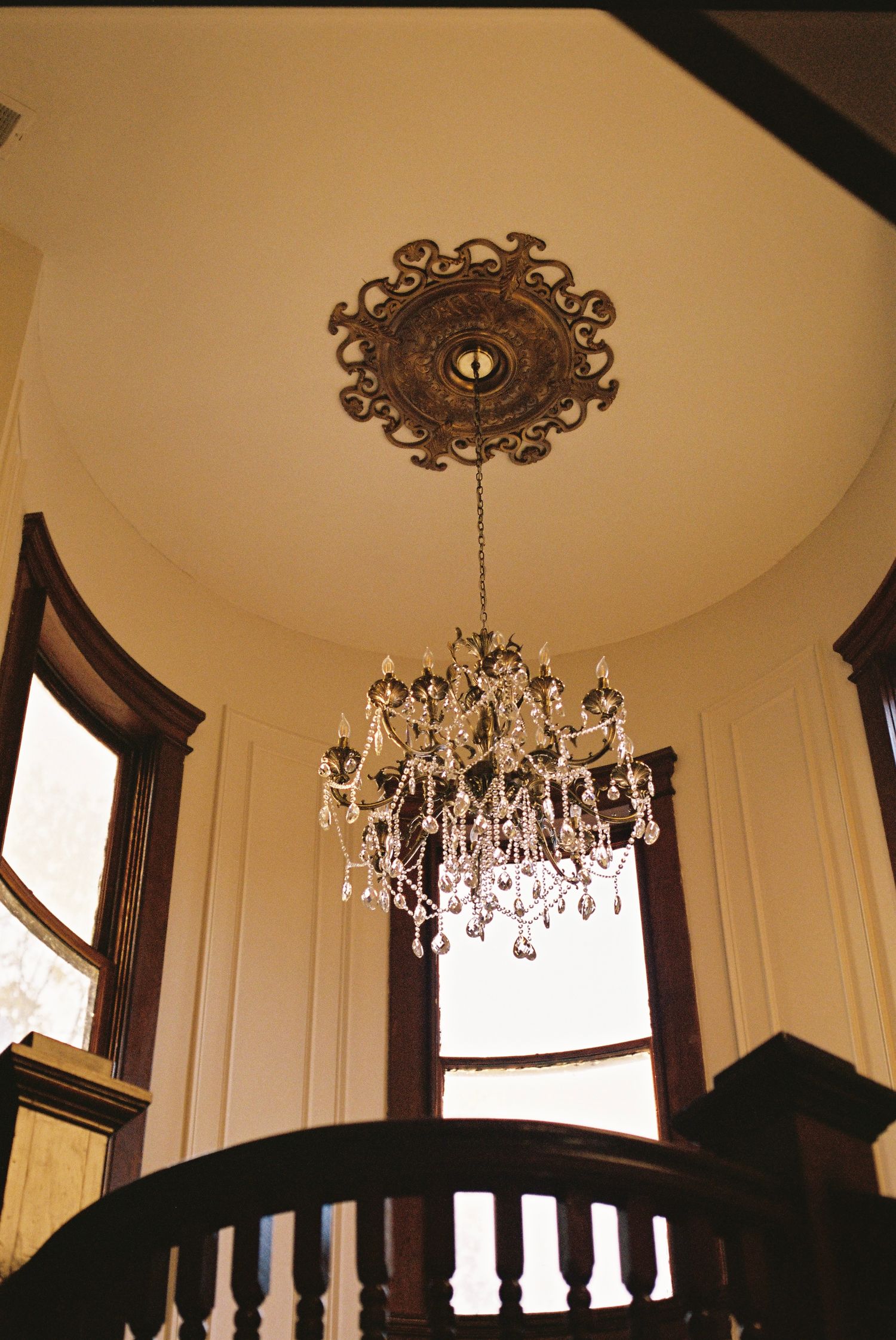 Elegant crystal chandelier hanging from ornate ceiling medallion in classic interior.