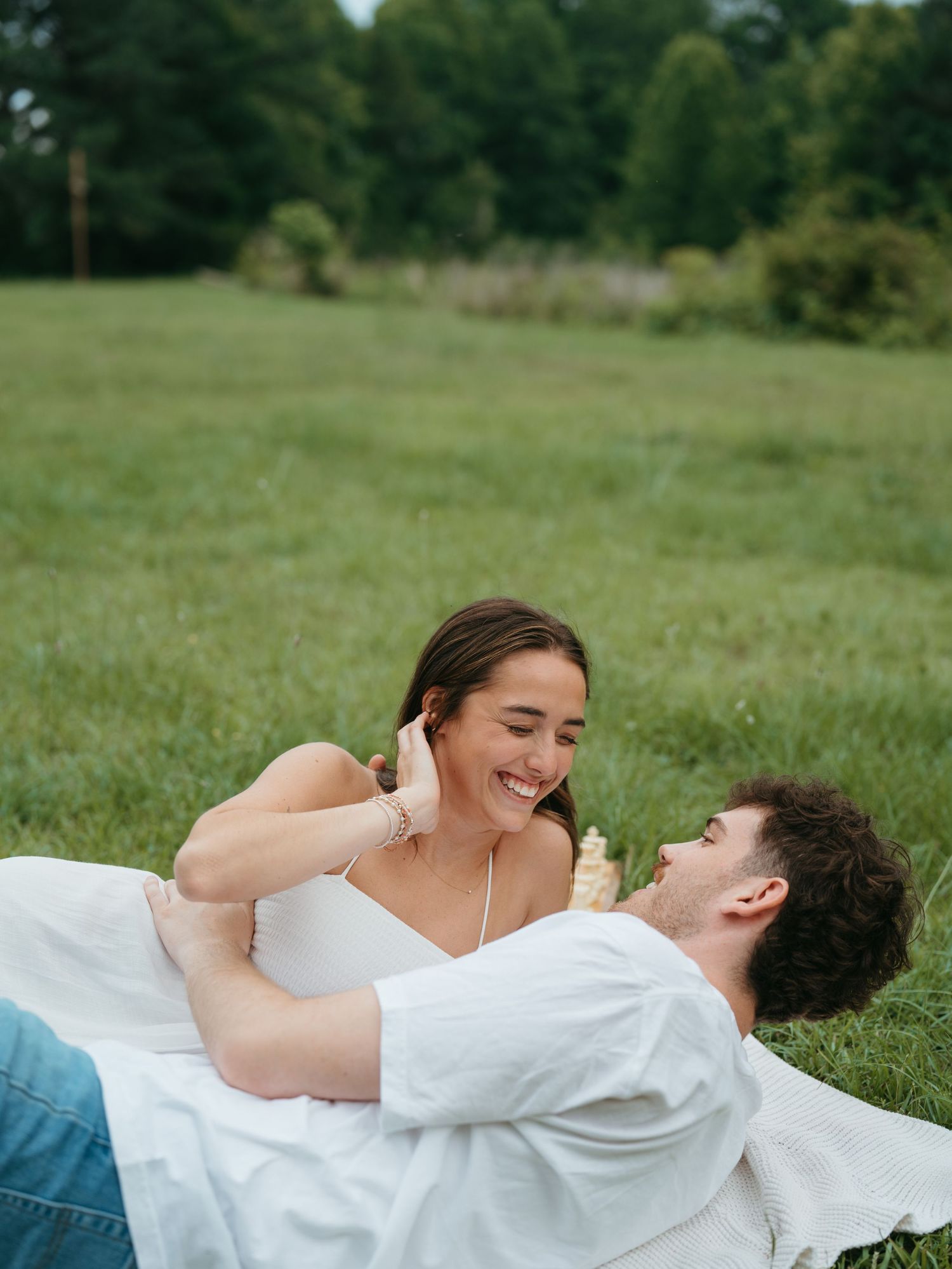 A couple lounges together on grass during a romantic outdoor photoshoot.