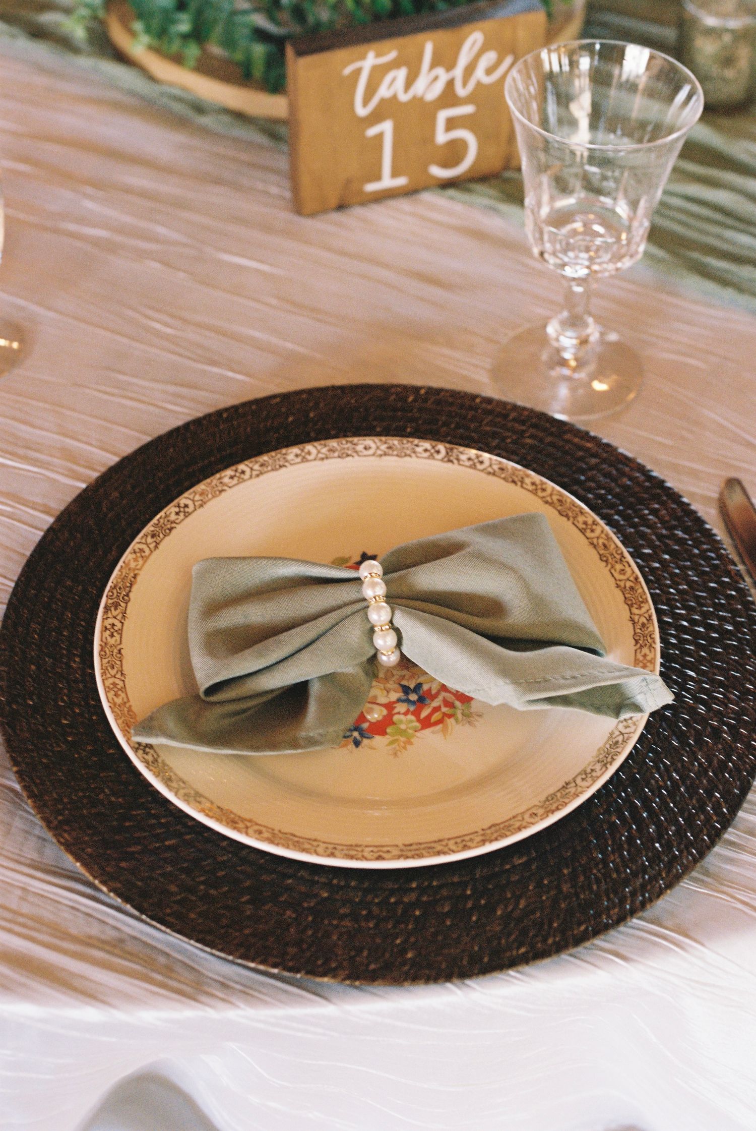 Place setting with silver bow napkin on black charger plate and table number.