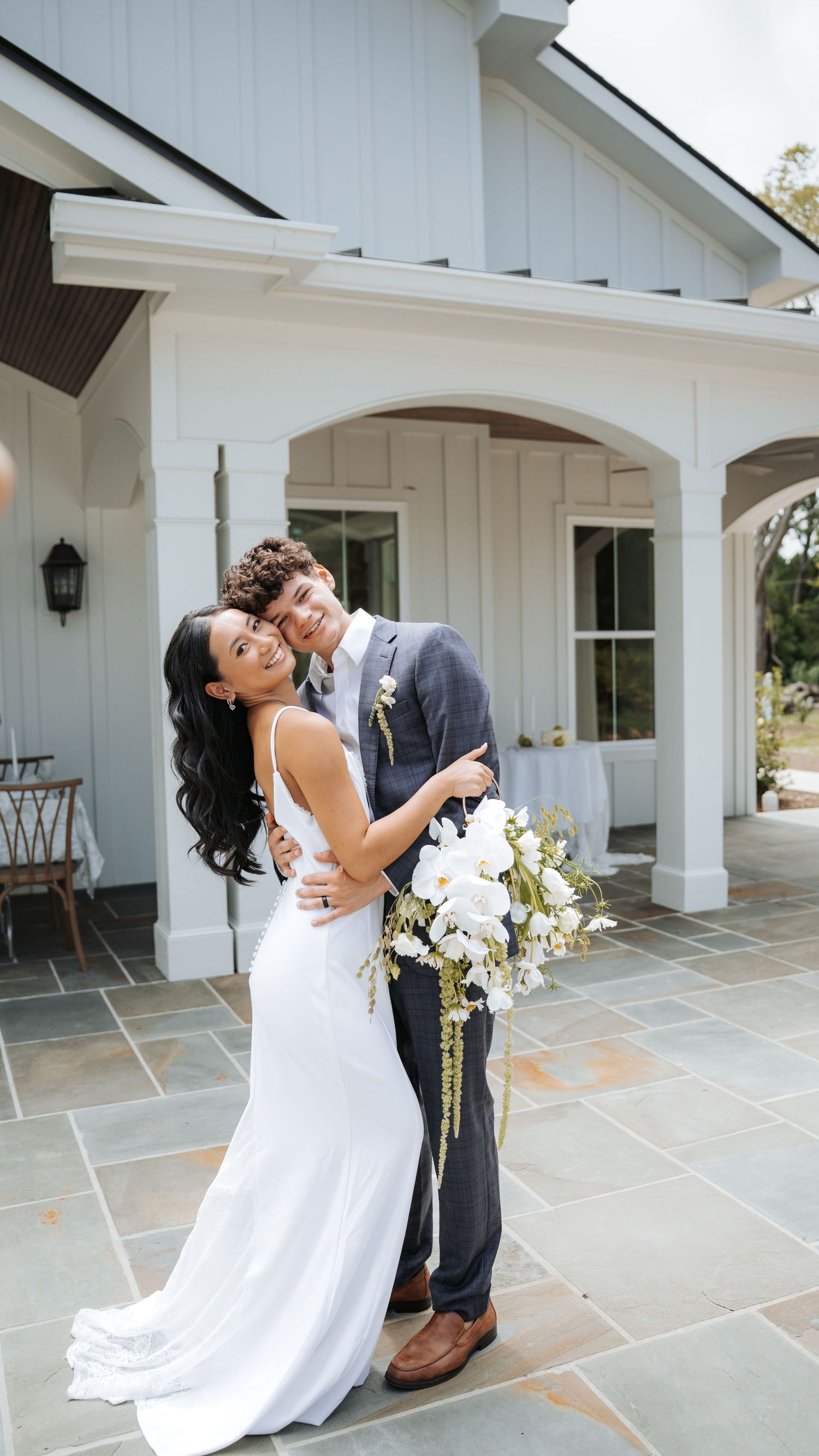 Romantic couple moment on stone patio outside white building with columns.