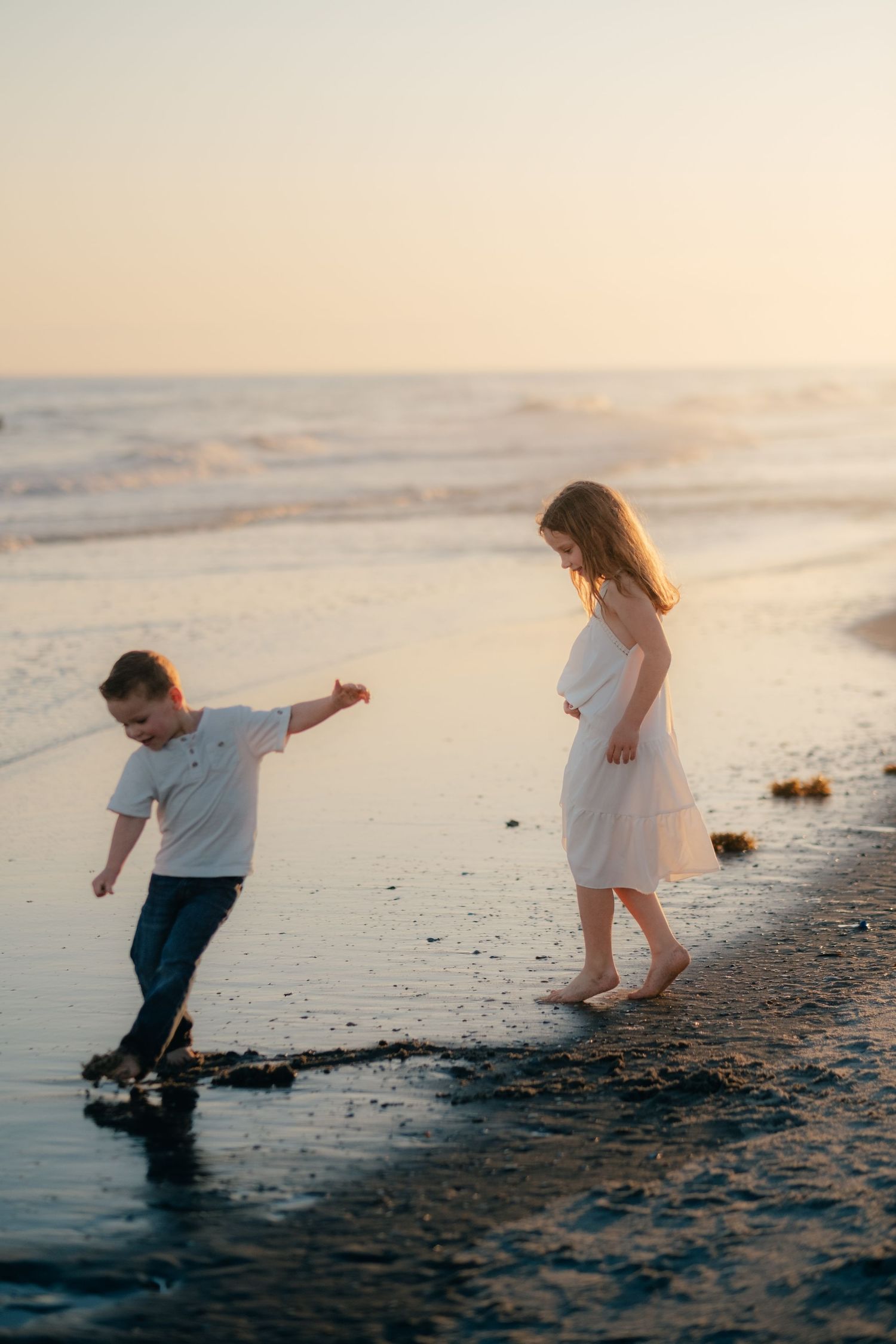 Children playing and splashing in the shallow waves at sunset.