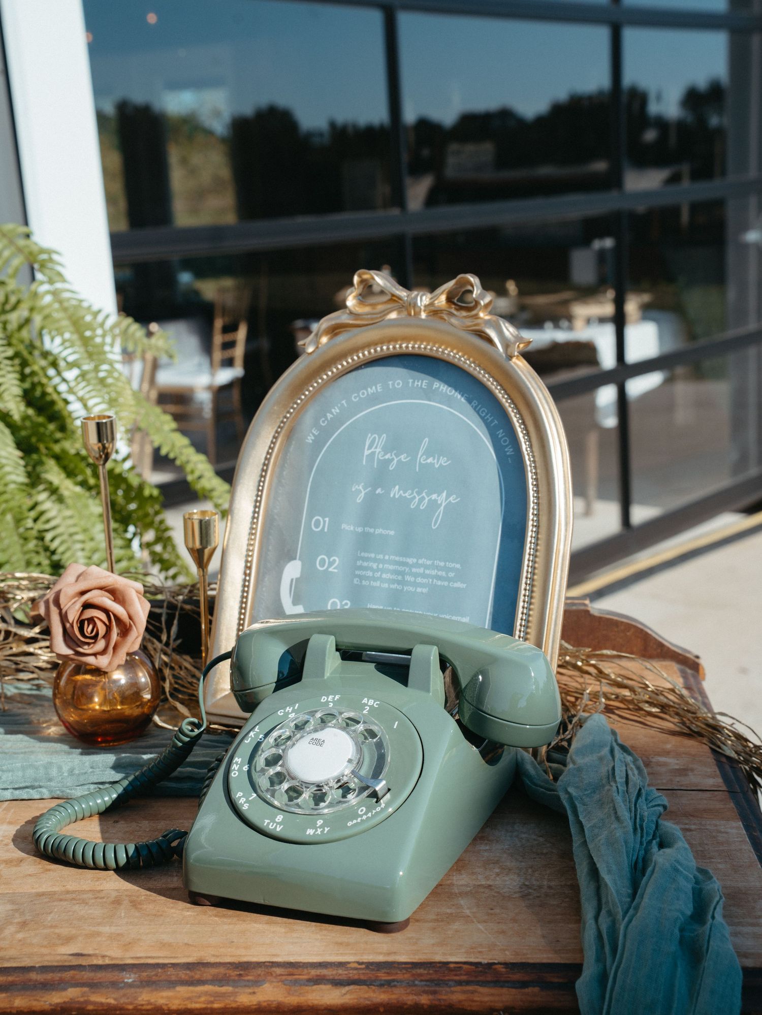 Vintage mint green rotary telephone with gold accents displayed on wooden surface with decorative frame and foliage.