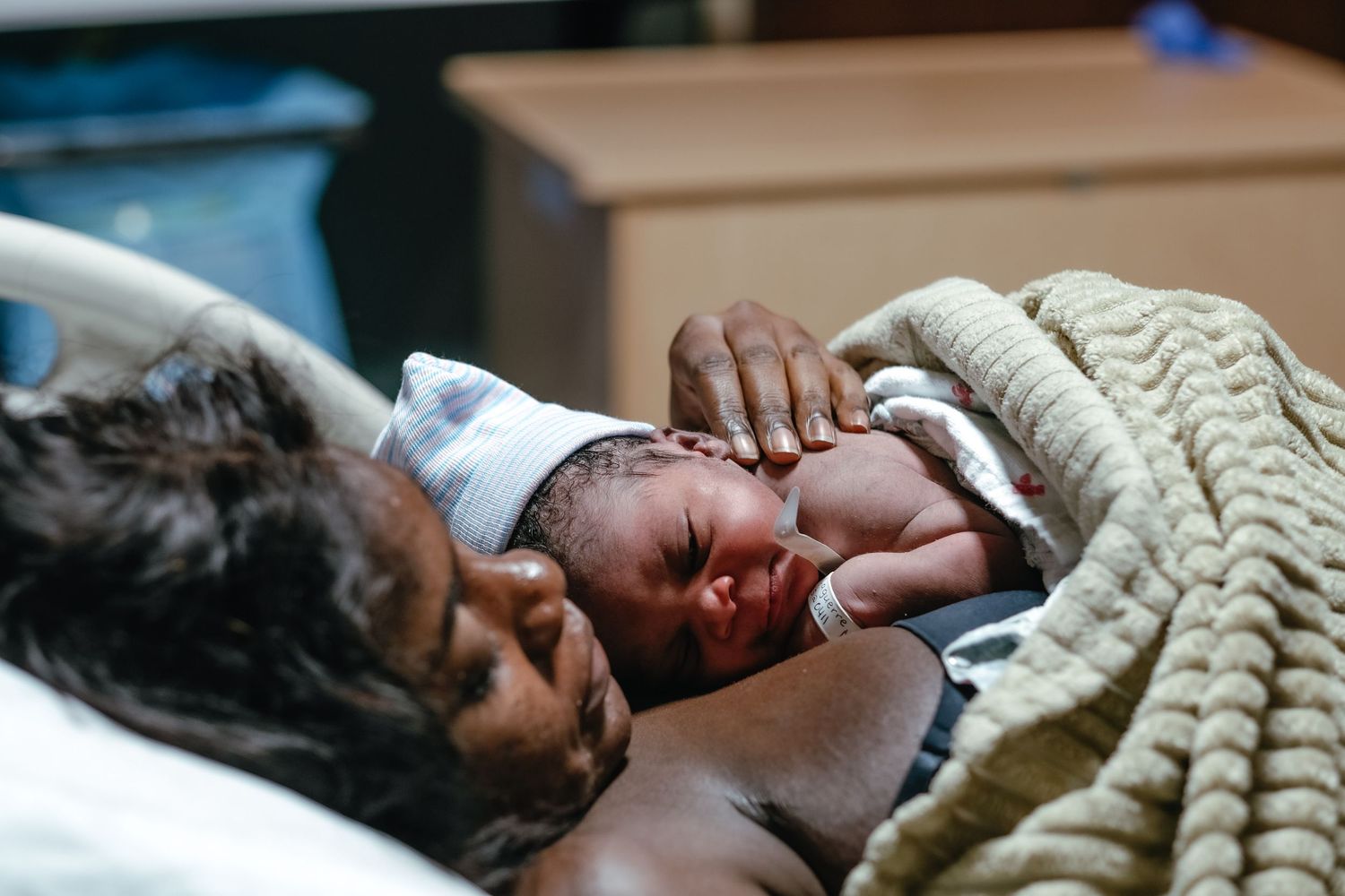 A sleeping newborn baby wrapped in cozy textured blankets in black and white.