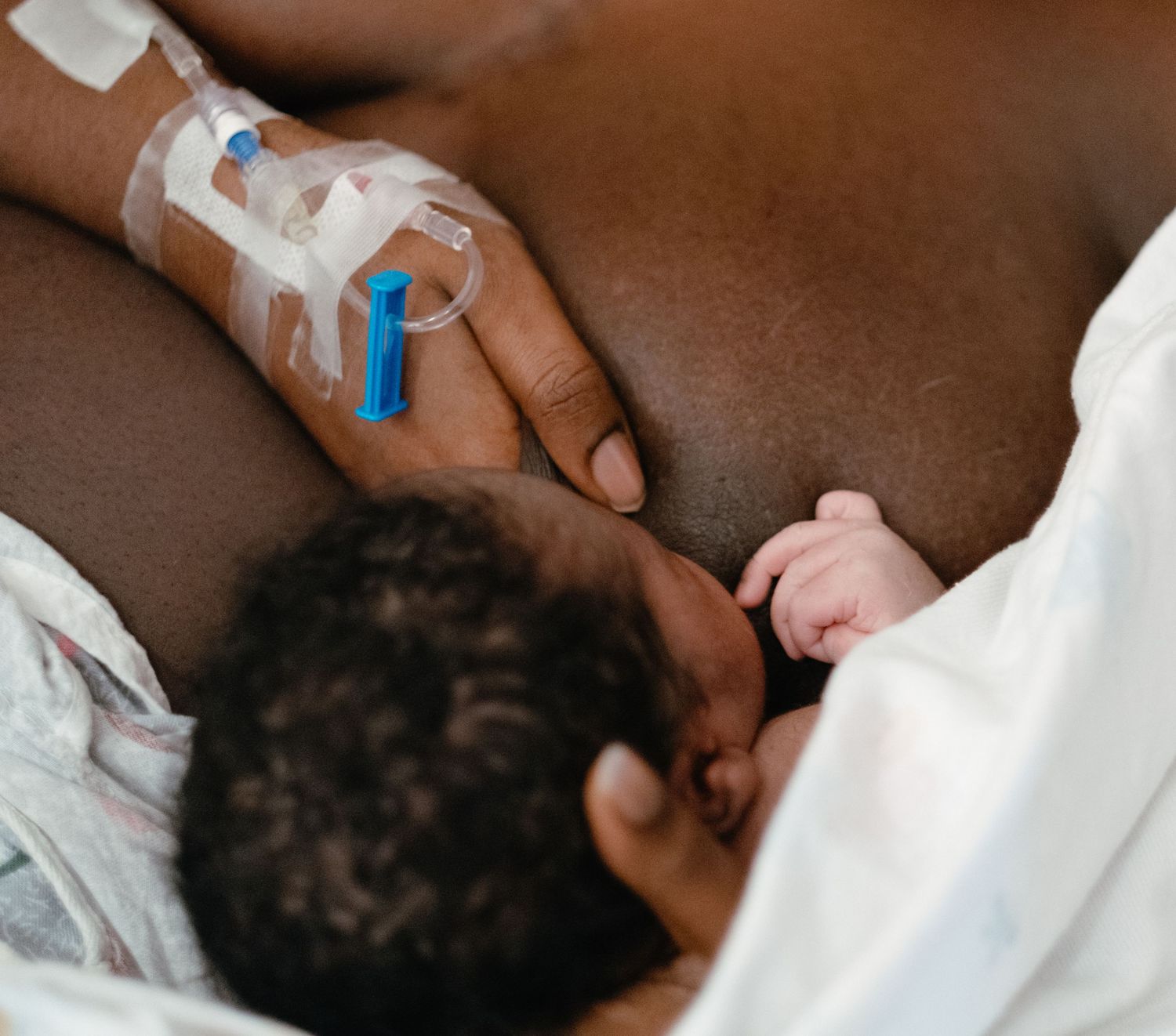 Medical professional wearing purple gloves examining newborn baby.