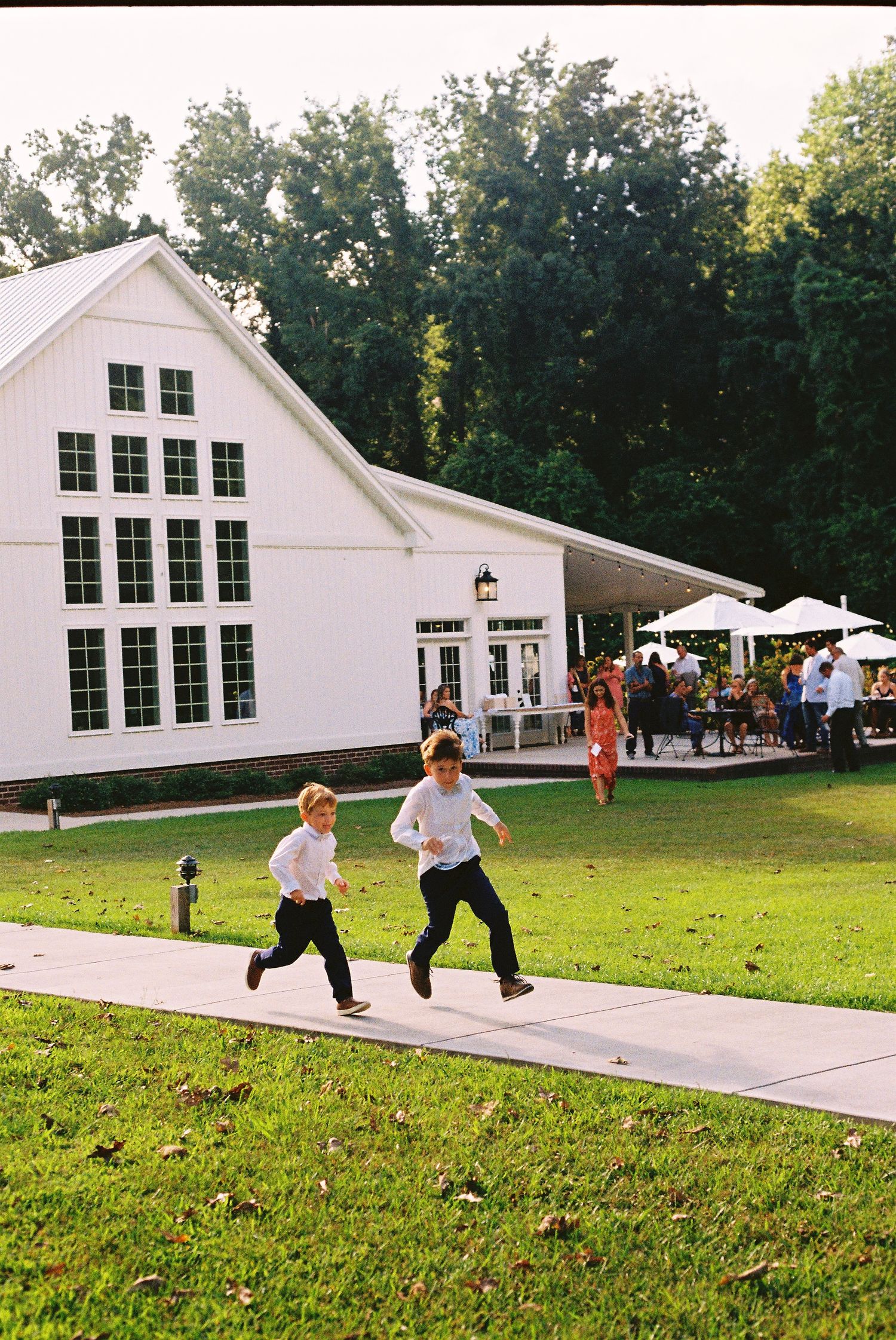 Children playing and running on a lawn in front of a white wedding venue building.