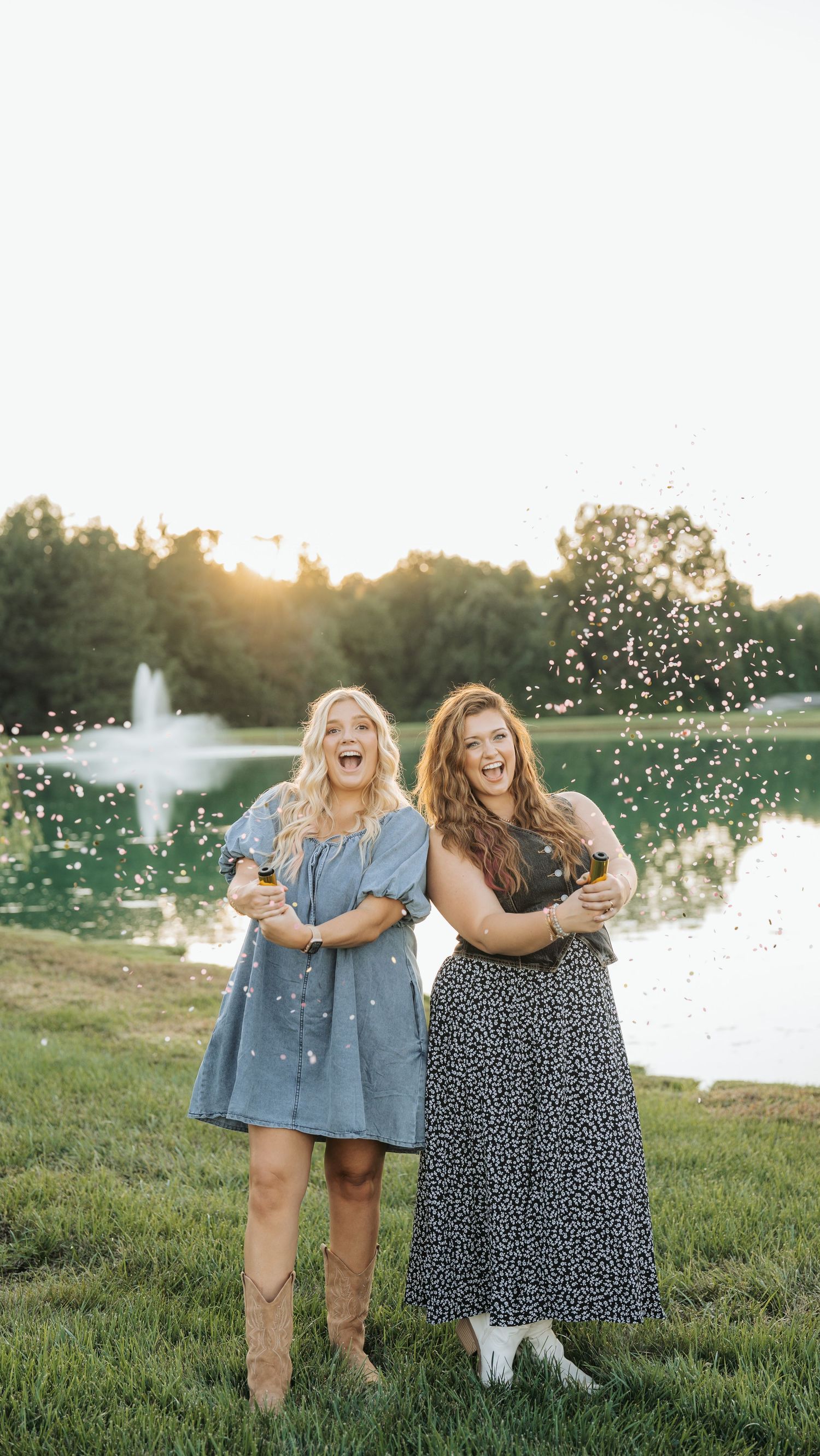 Friends celebrating outdoors by a fountain with sparklers at sunset.