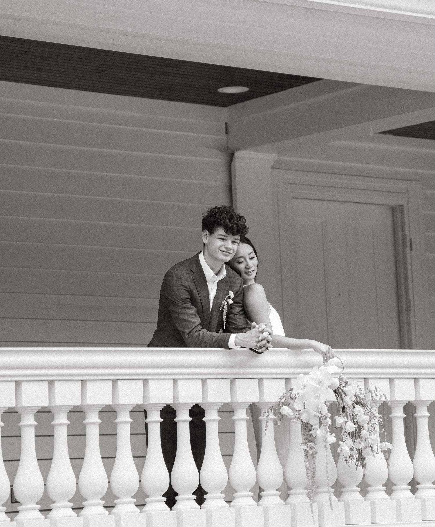 Elegant white porch railing of a wedding venue decorated with floral arrangements.