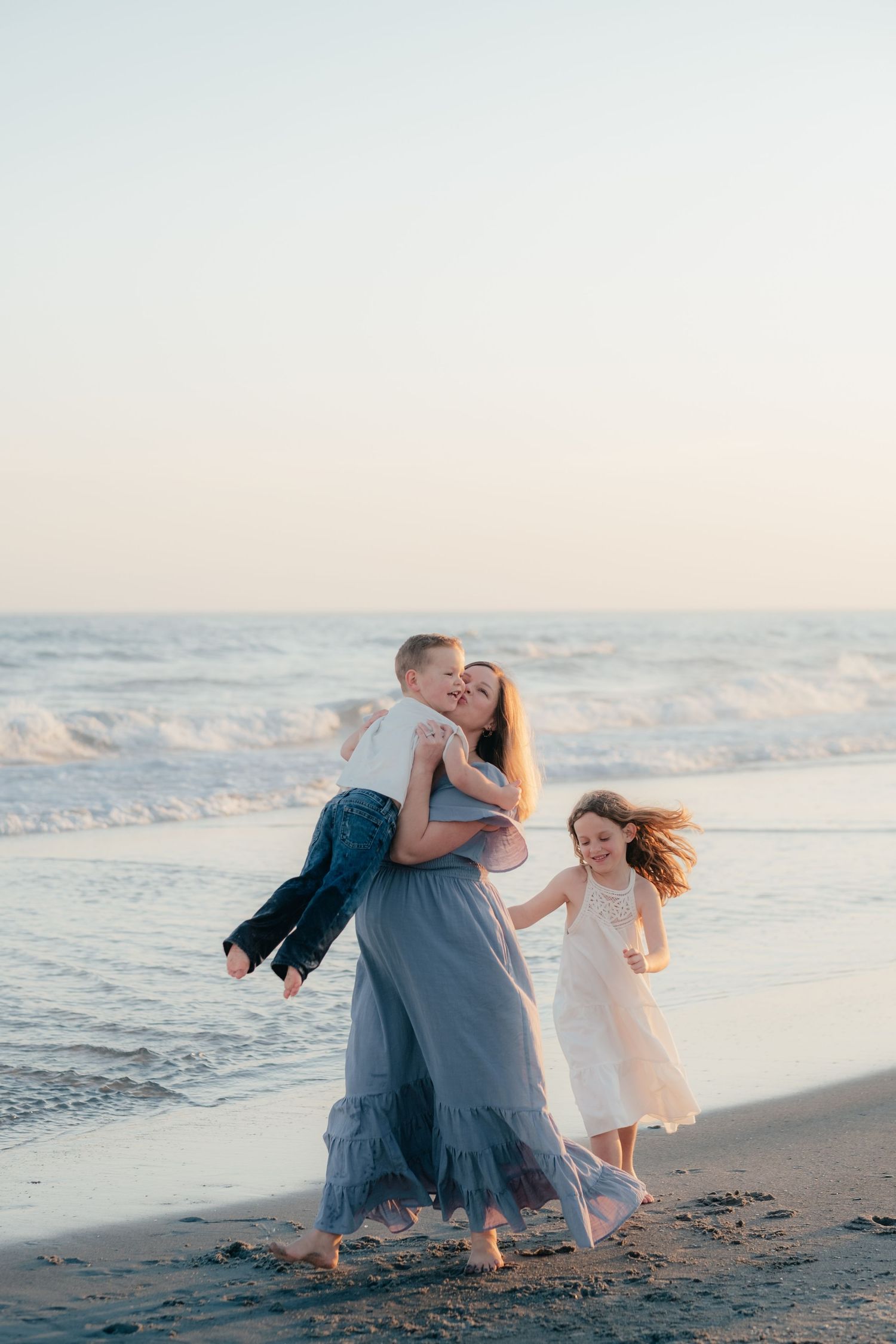 Joyful family interaction on beach with crashing waves at sunset.