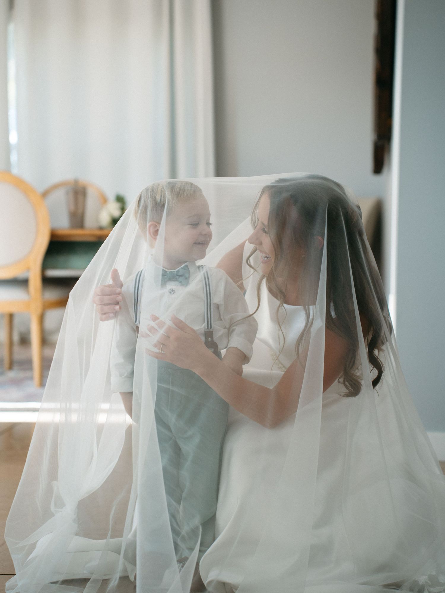 A series of tender moments between a bride and child captured through delicate white wedding veil in soft natural light.