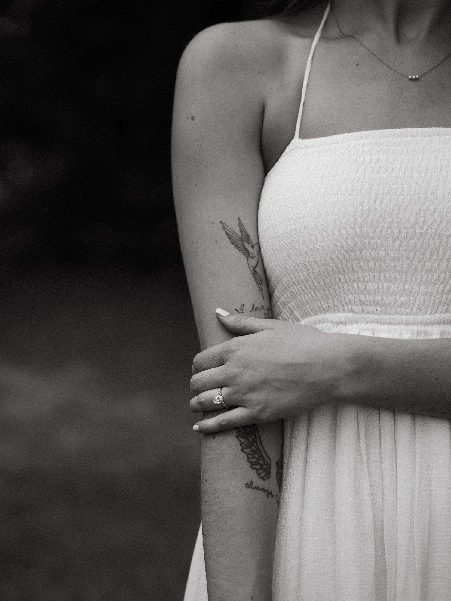 Close-up of a white smocked sundress and arm details in black and white.