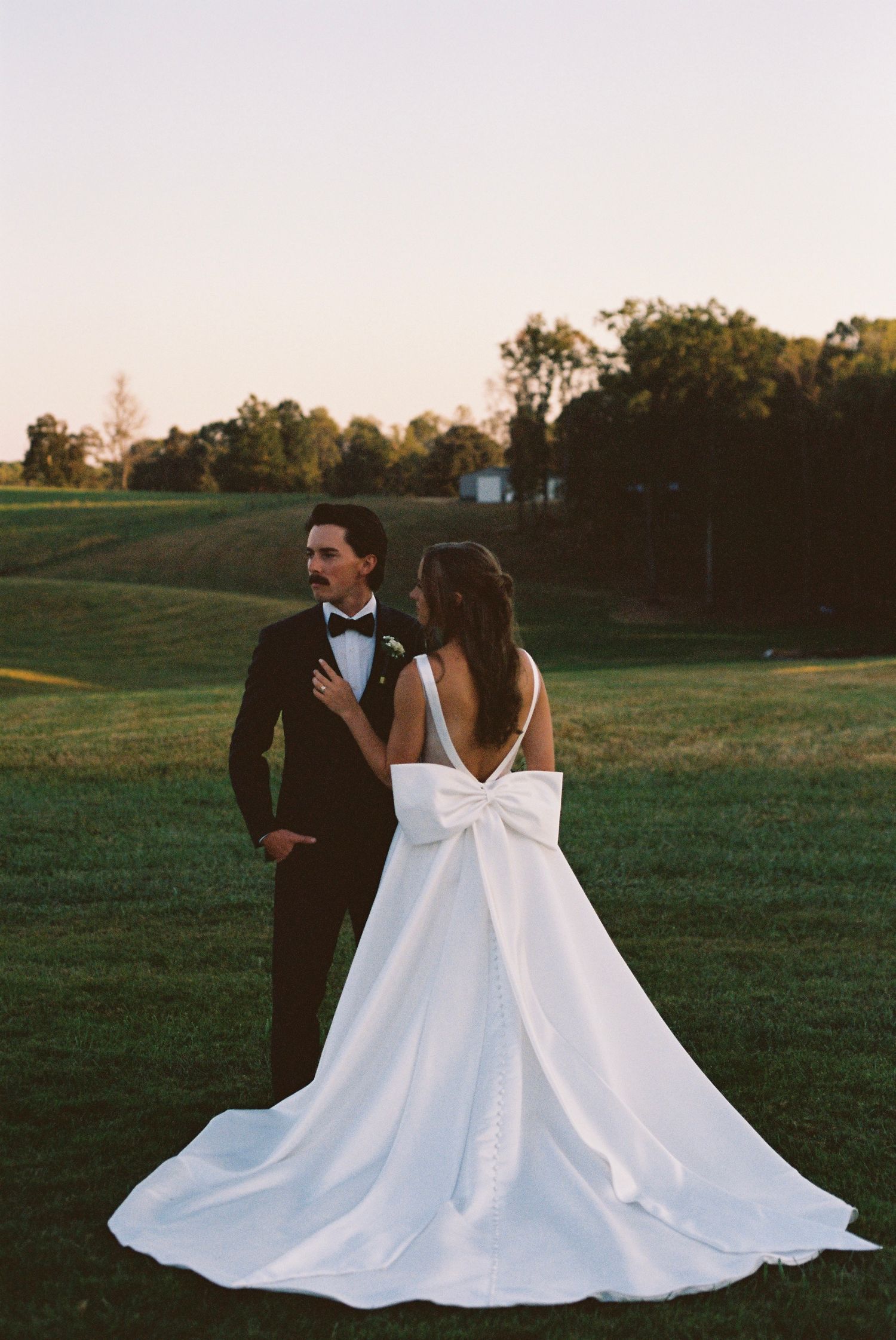 A couple on their wedding day captured on film an intimate moment in a golden field at sunset.