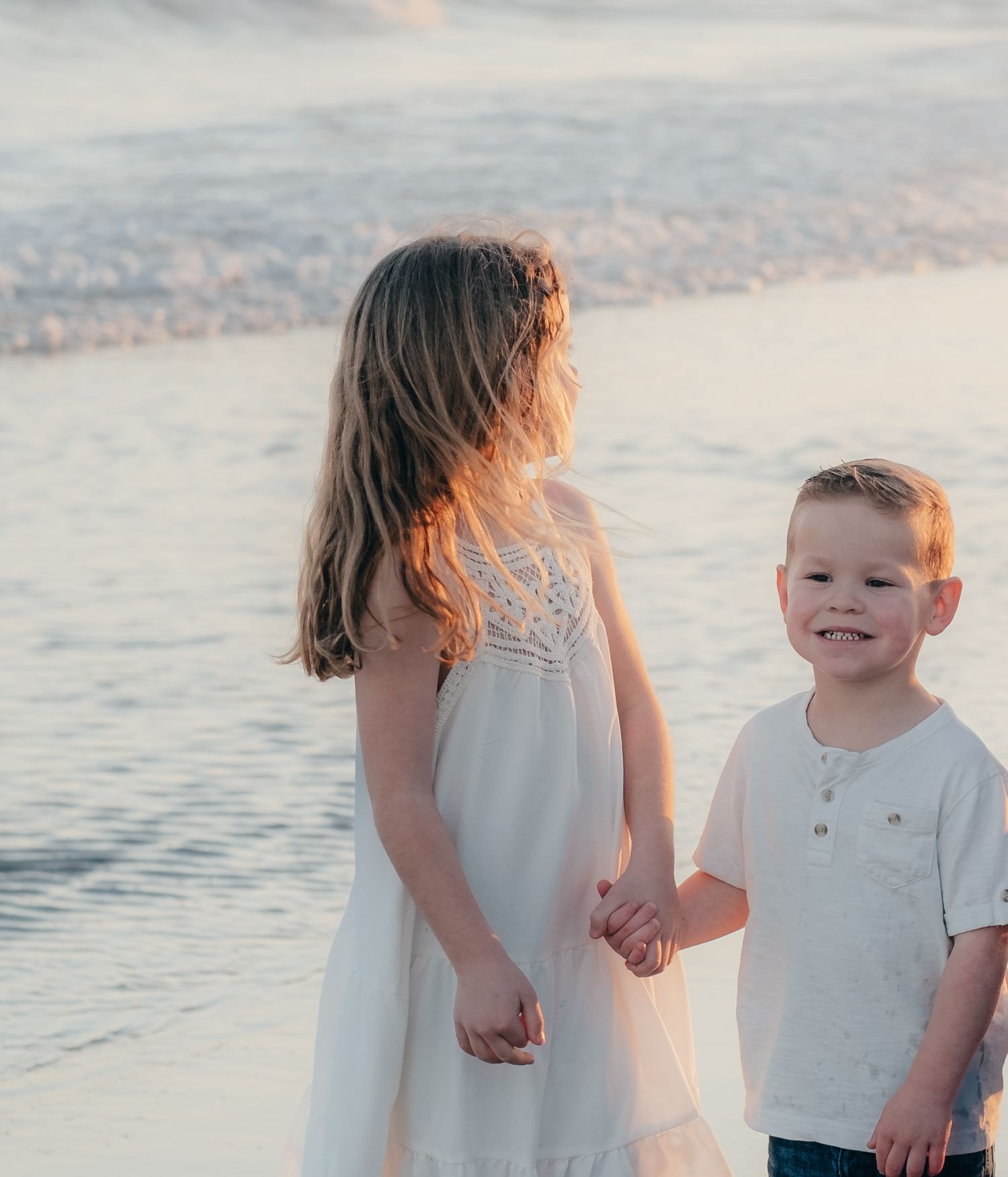 Family walking hand in hand along the beach at sunset.