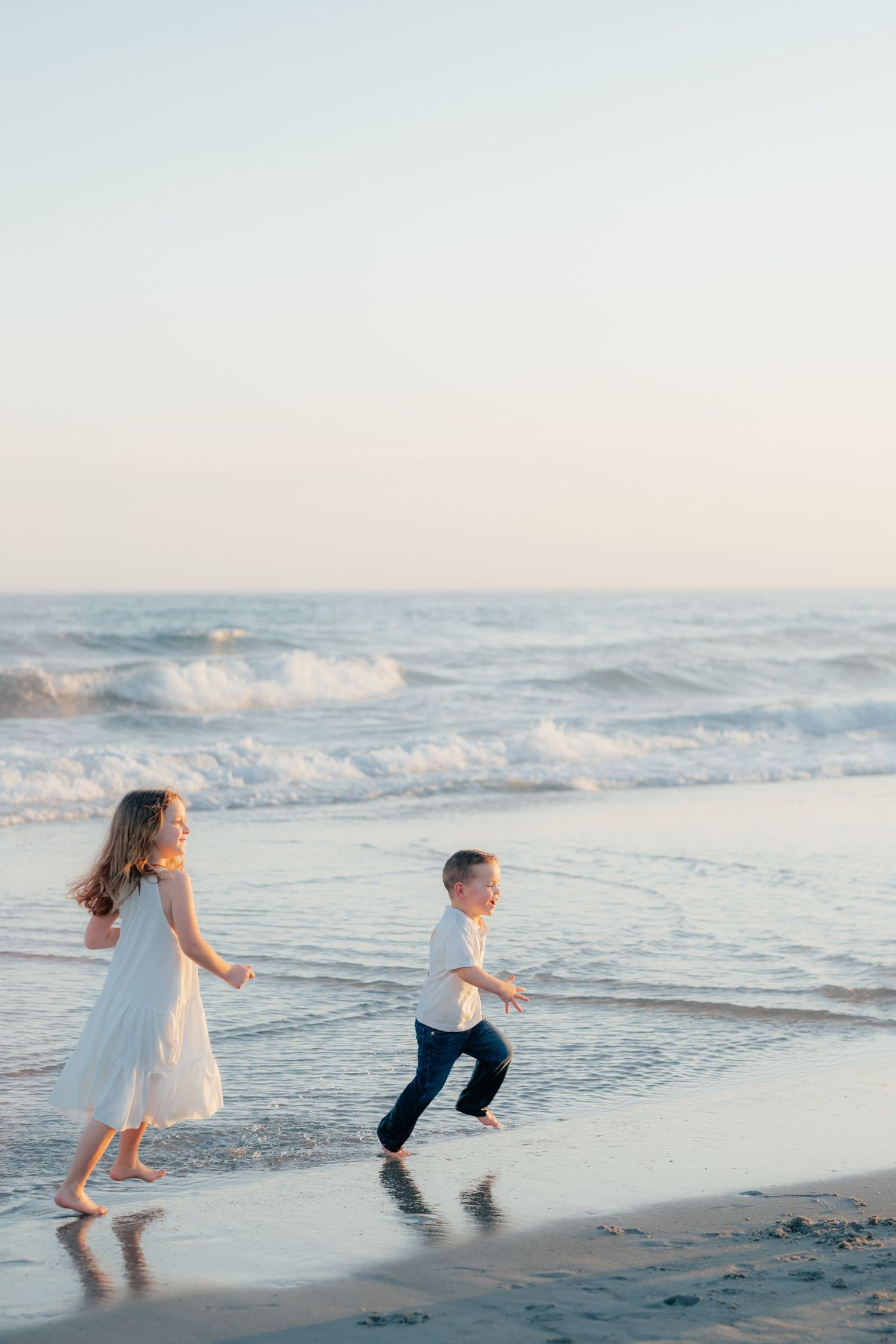 Children running and playing in the surf during a beach photoshoot.