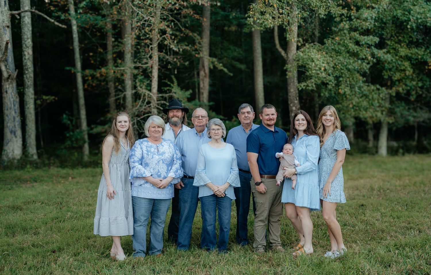 Extended family group photo in coordinated blue and white outfits outdoors.