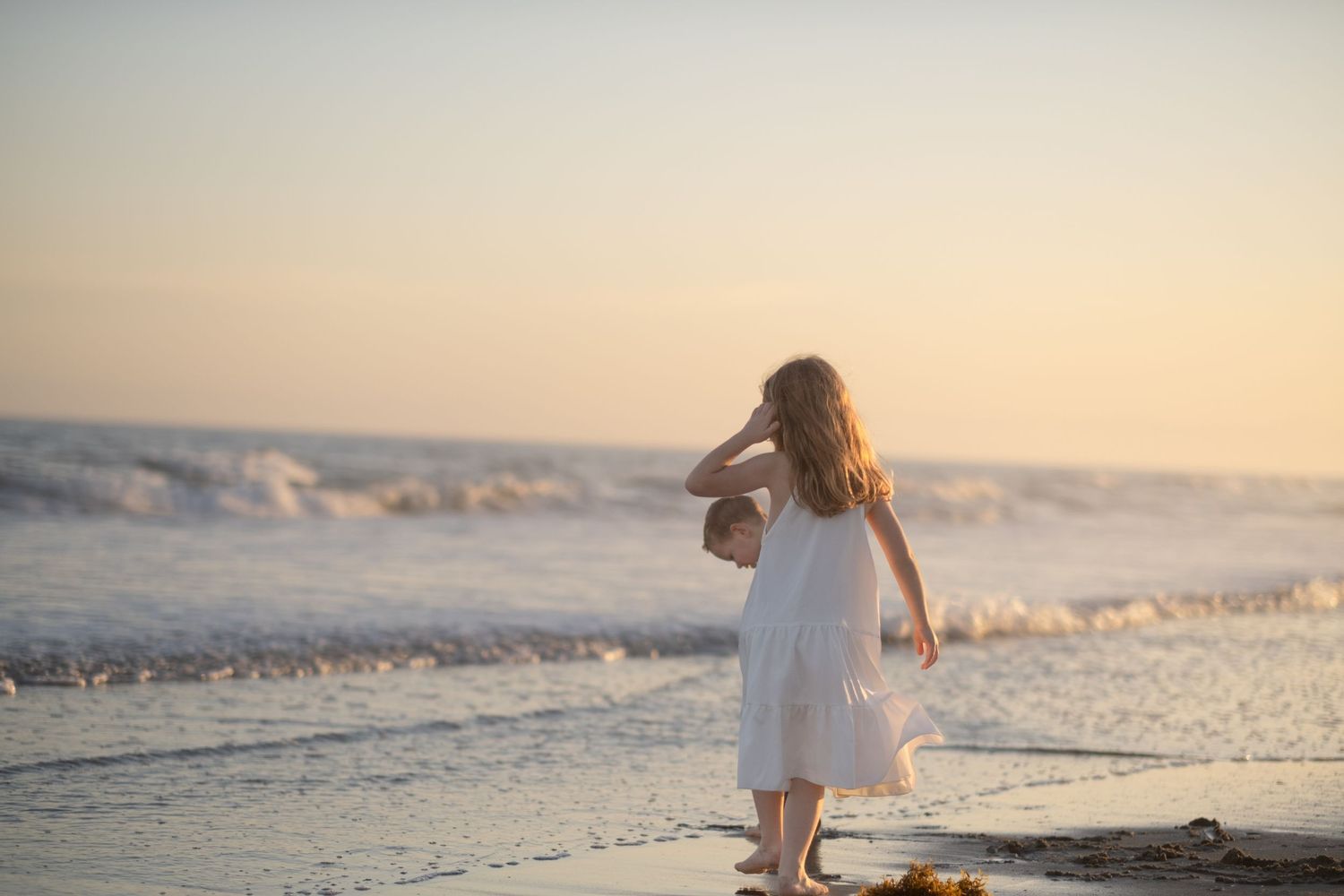 Beachside family portraits with soft pastel sunset colors and rolling waves.