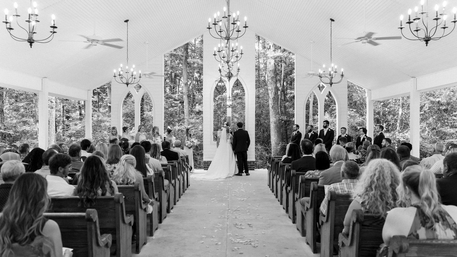 A black and white panoramic collage of a wedding ceremony showing multiple angles of guests seated in church pews.