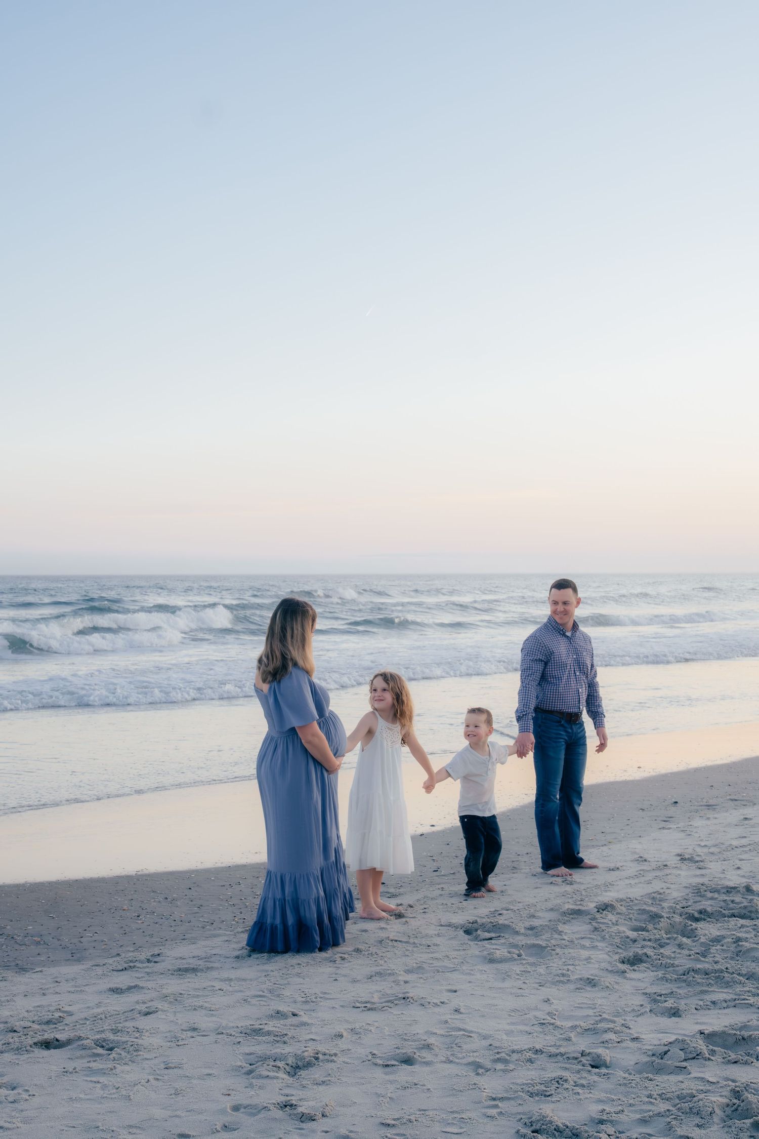 Family spending time together on sandy beach during golden hour.