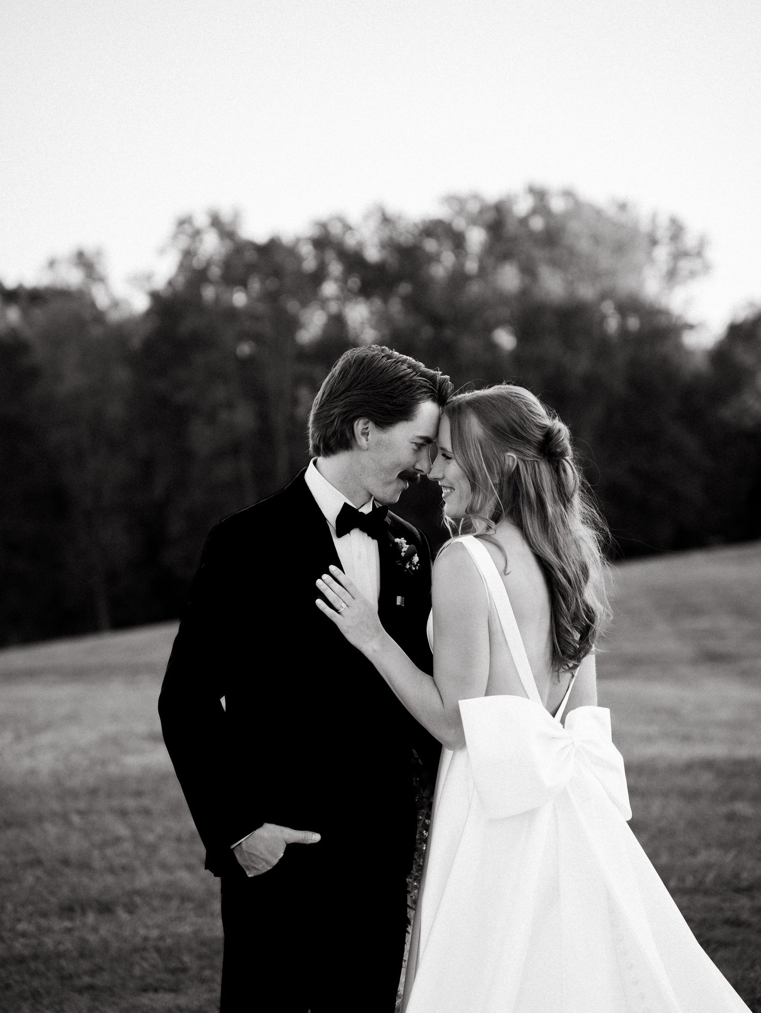 A romantic black and white wedding photo sequence showing a couple sharing intimate kisses in an outdoor field setting.