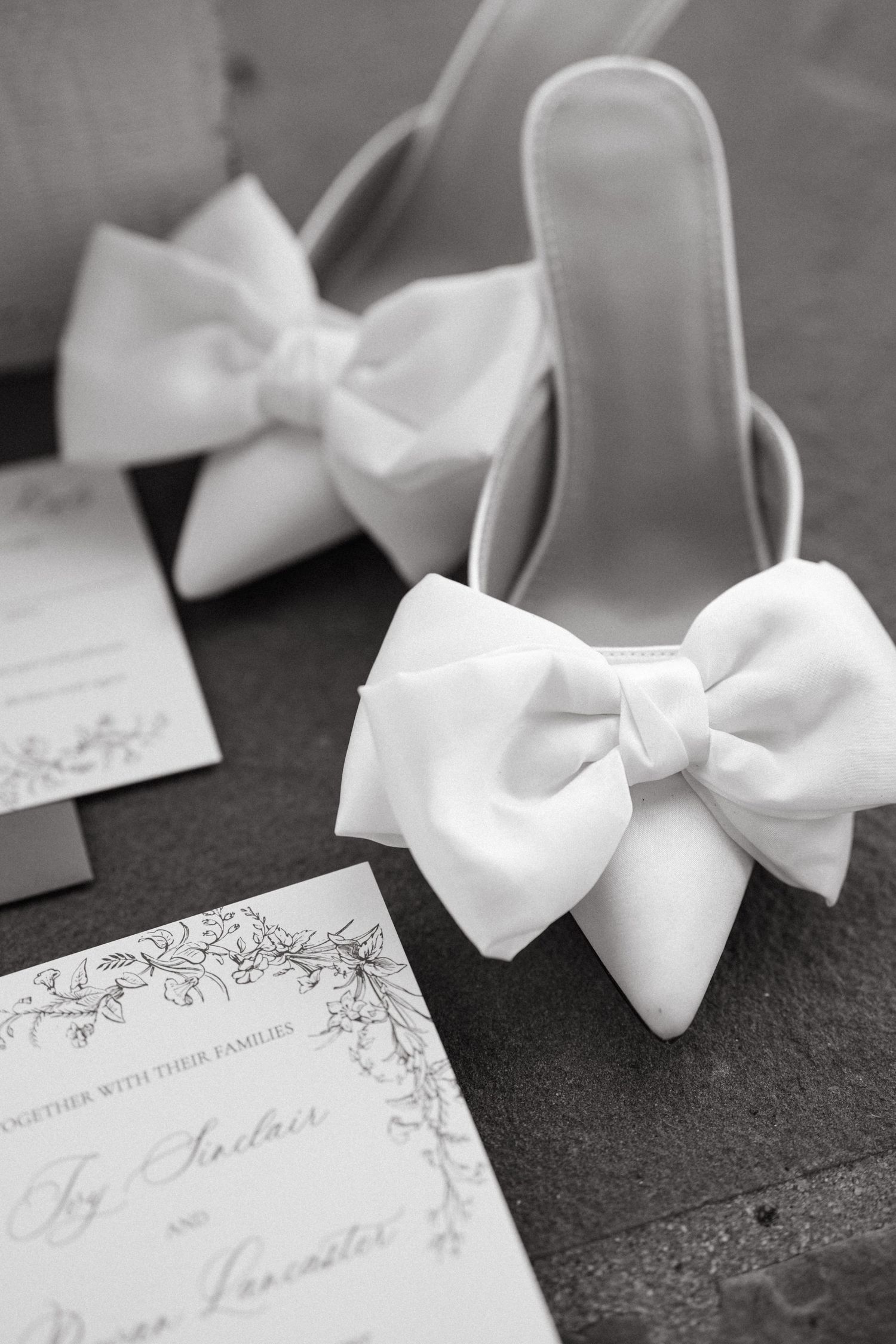White satin bows and elegant wedding stationery on a dark surface.