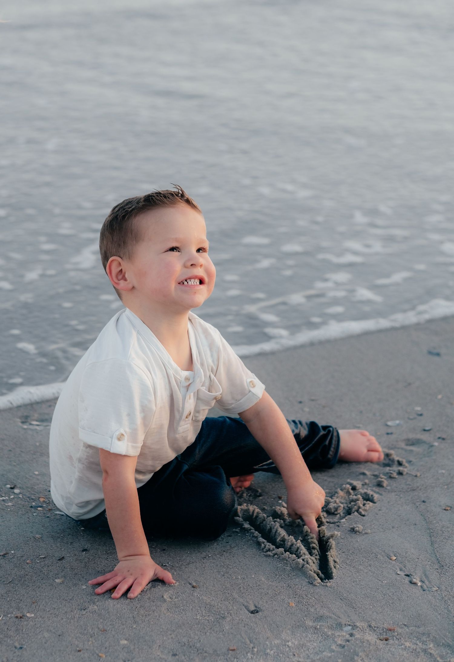 Child playing in the sand at the beach during sunset.