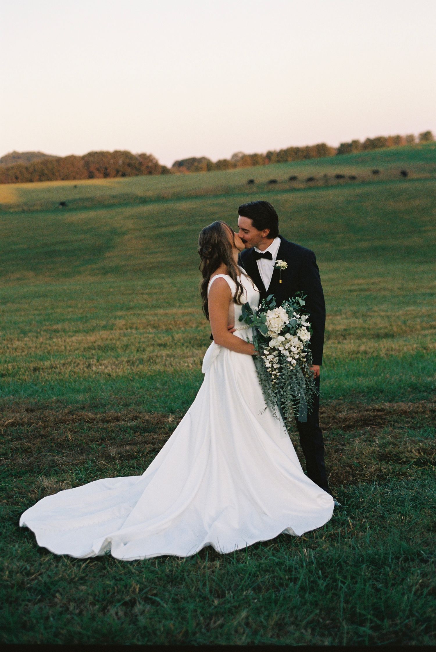 A romantic wedding photo session captured on film in a scenic field during golden hour.