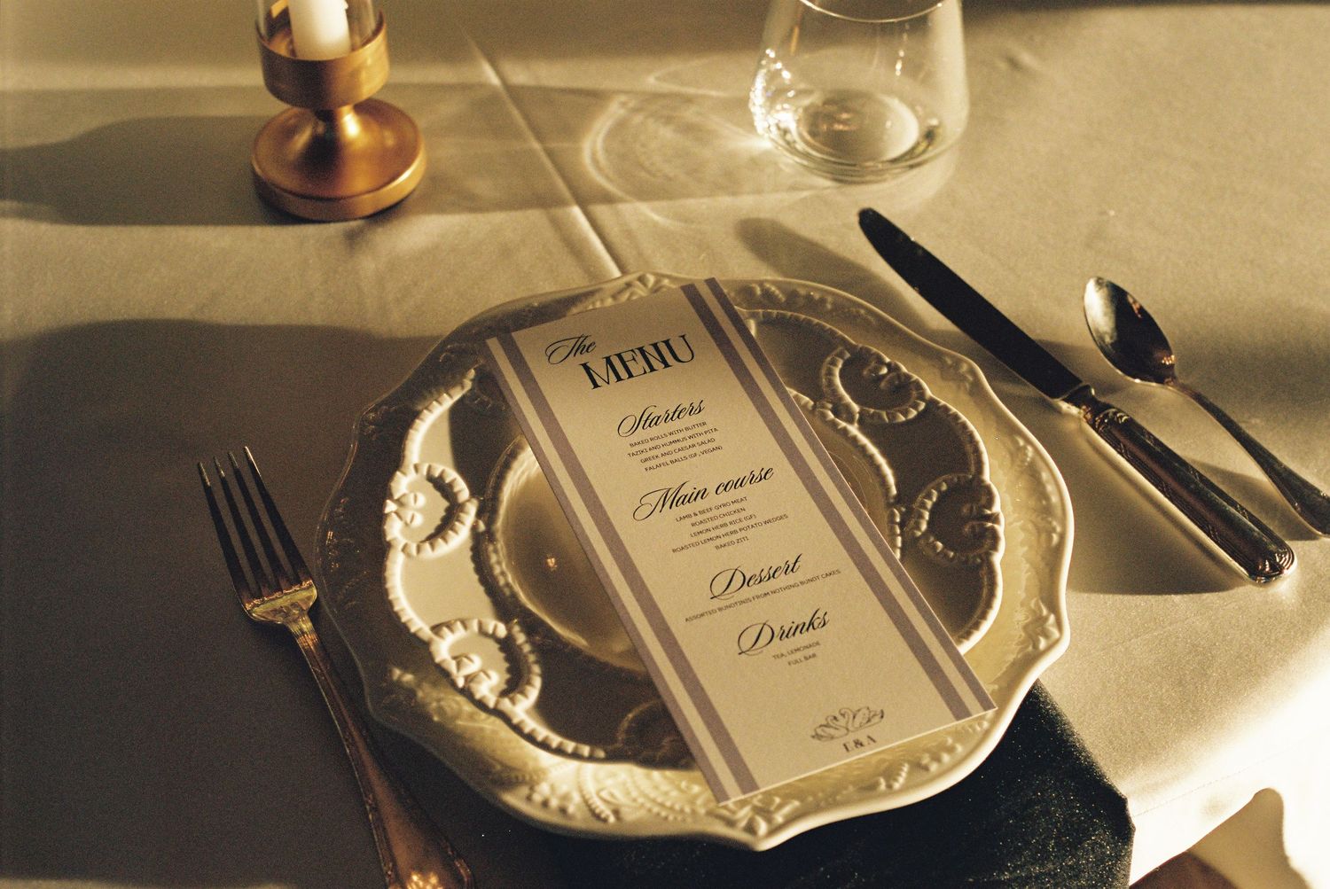 Wedding place settings with elegant plates and cutlery on cream tablecloth.