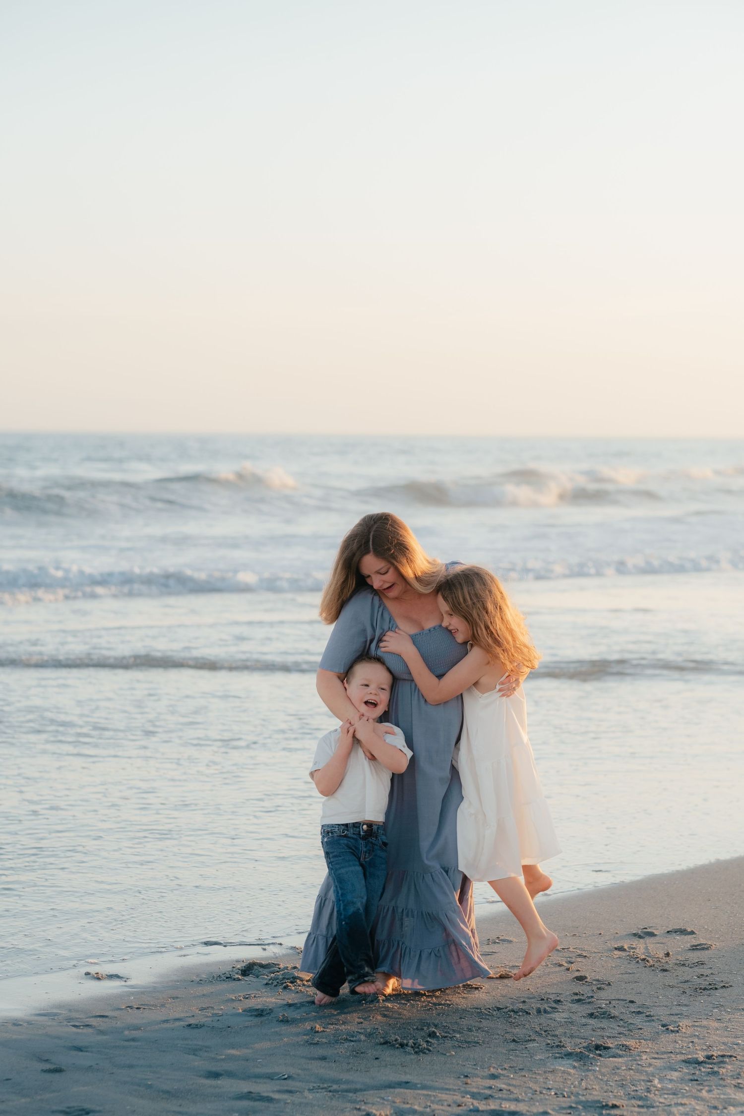 Loving family embrace on the beach with ocean waves in the background.