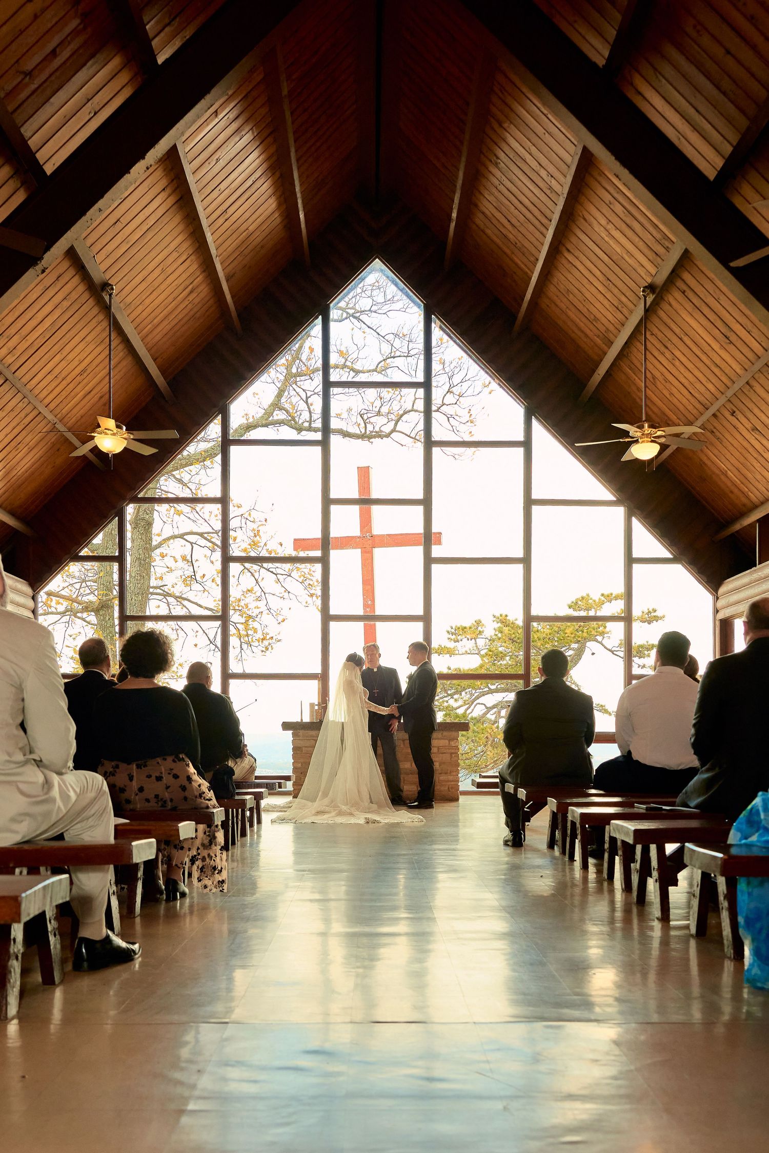 A panoramic view of a church interior with wooden beams and large windows during a gathering of attendees.