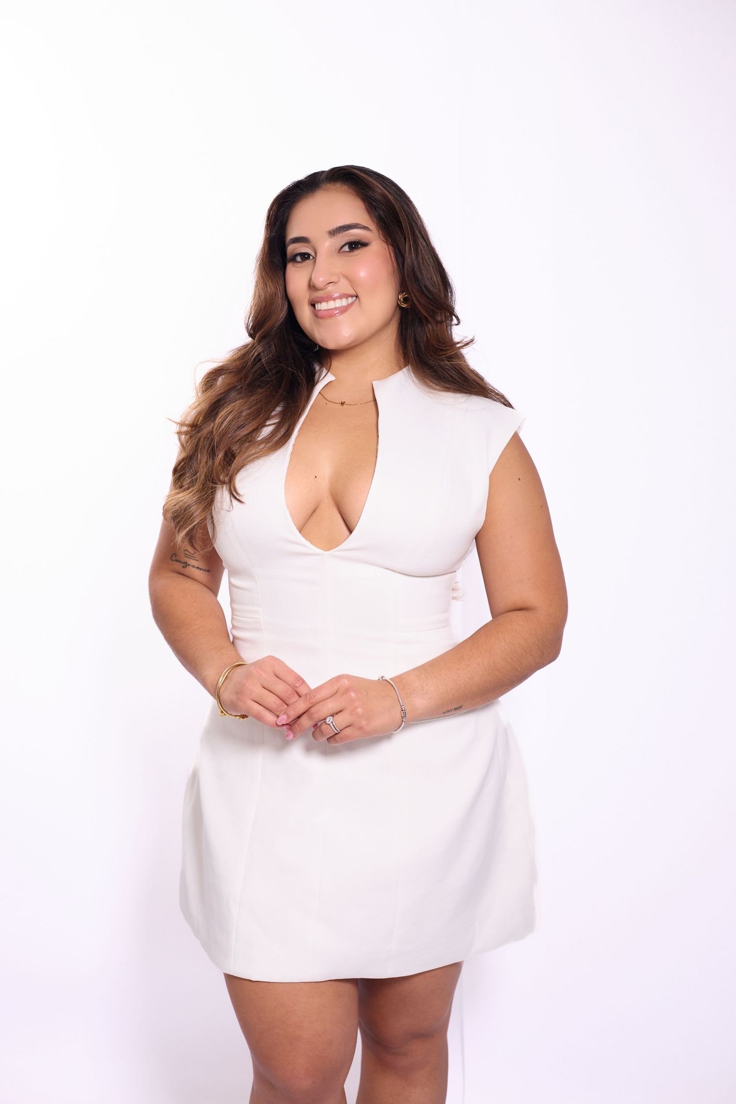 Plus size model in white dress poses confidently against white background in studio photoshoot series.