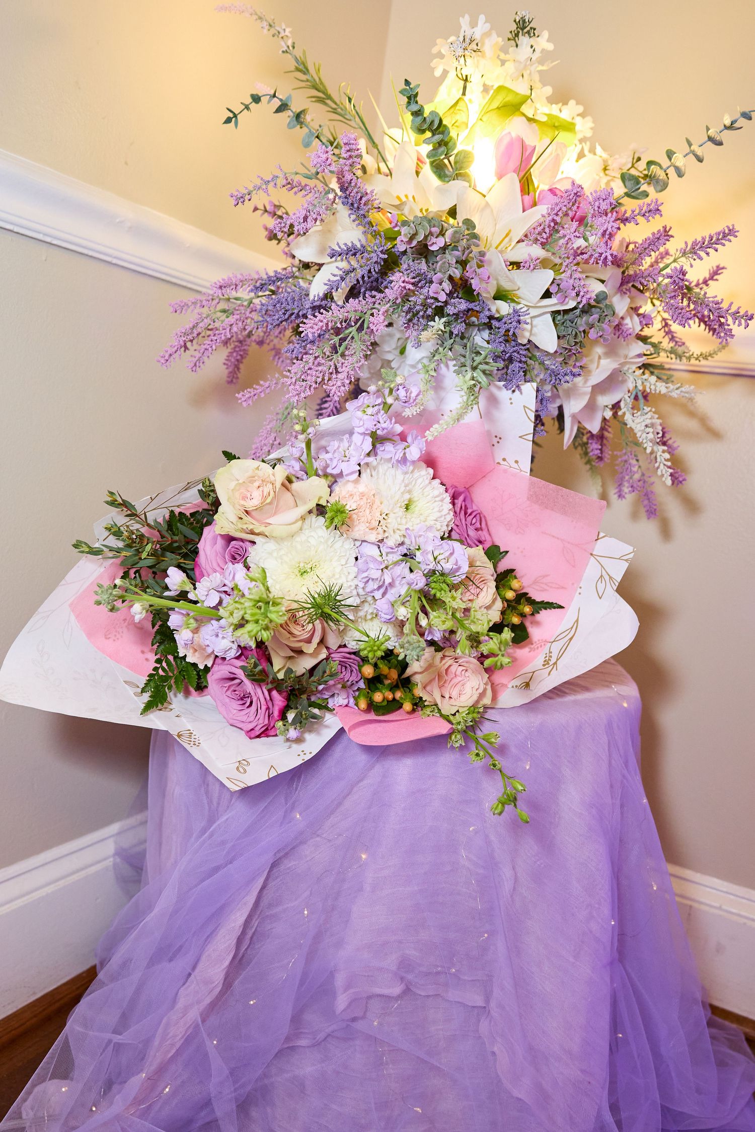 A romantic floral arrangement with pink and purple flowers adorns a lavender tulle-draped table setting.