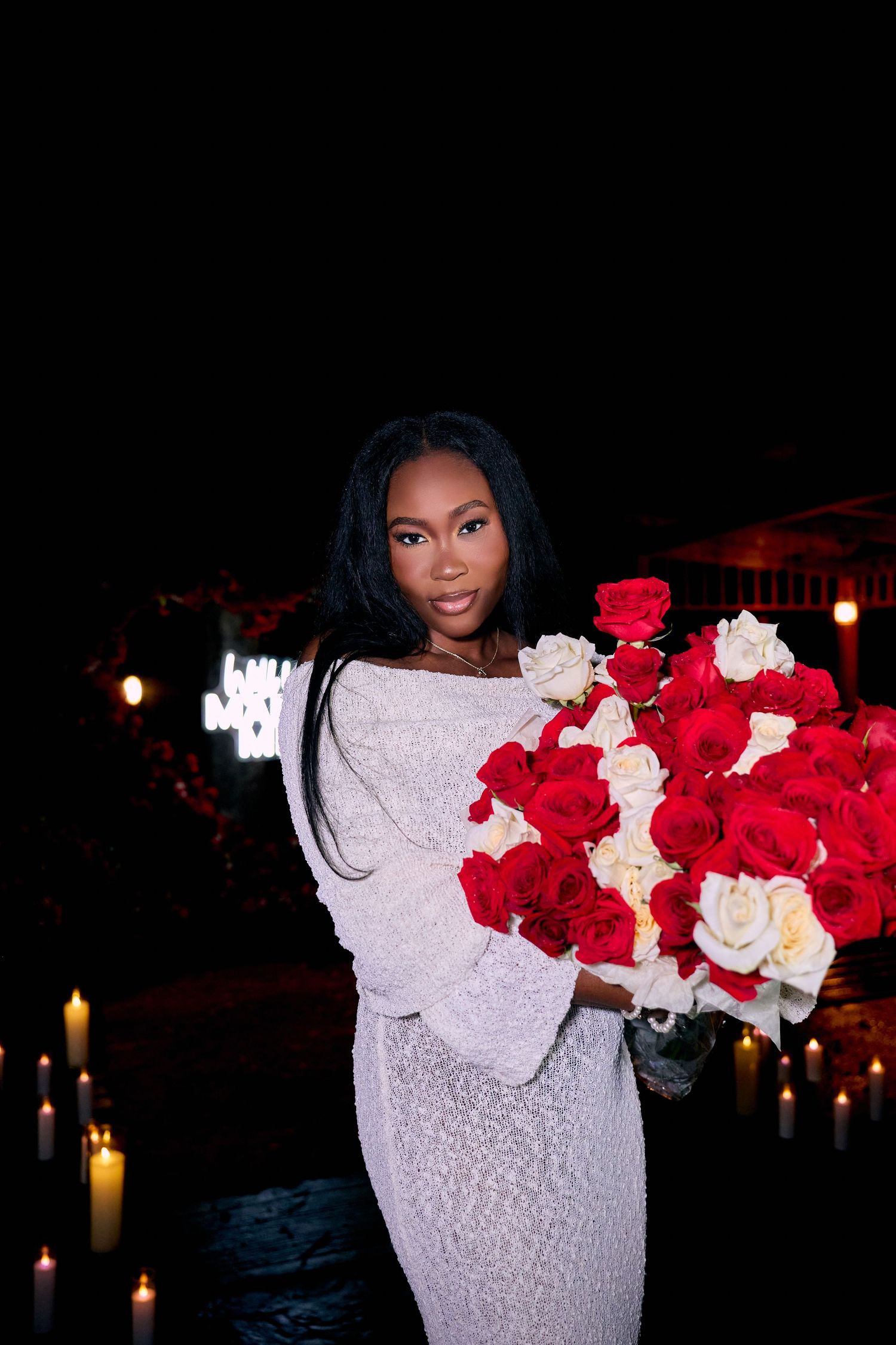 A romantic scene with red and white roses arranged against a dark backdrop with glowing candlelight.