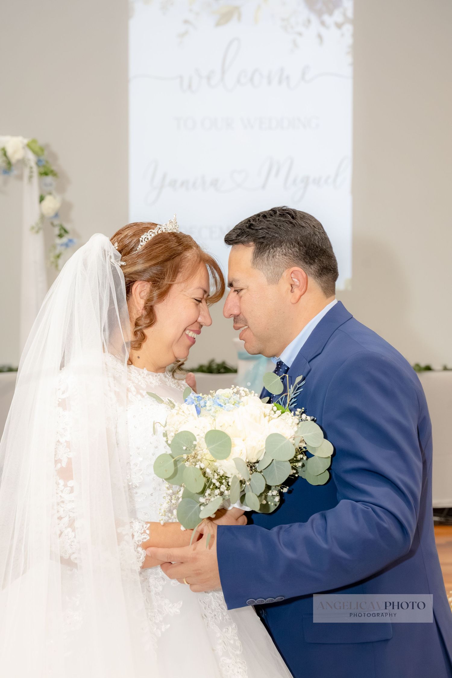 Wedding ceremony moment with white floral backdrop and bouquet.