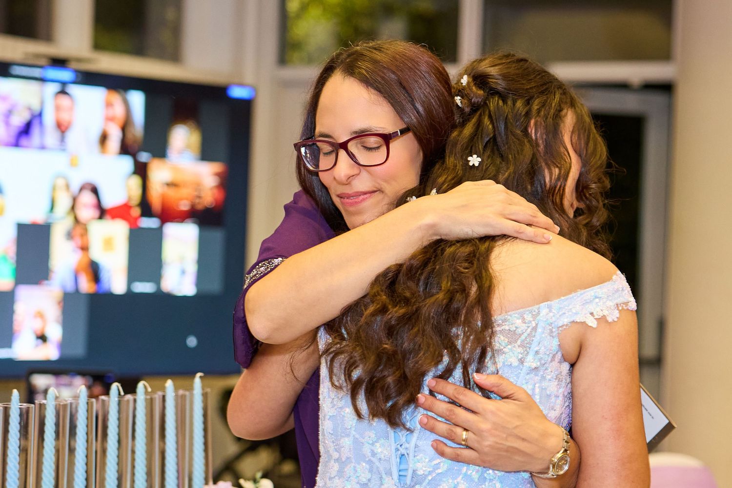 Joyful wedding guests embrace and celebrate during an emotional reception moment.