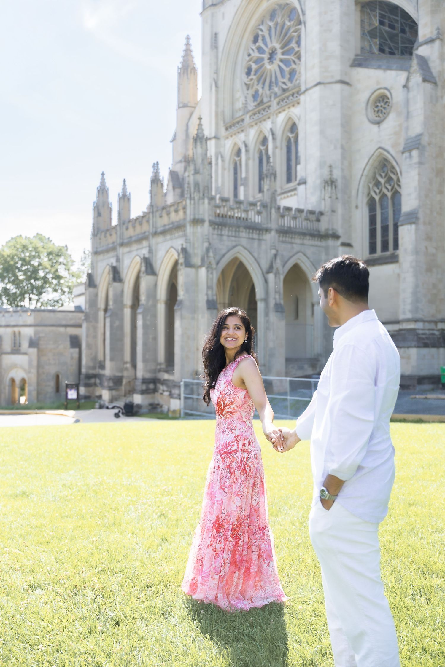 Couple enjoying a romantic photoshoot on a sunny day in front of a grand Gothic cathedral with ornate architecture.