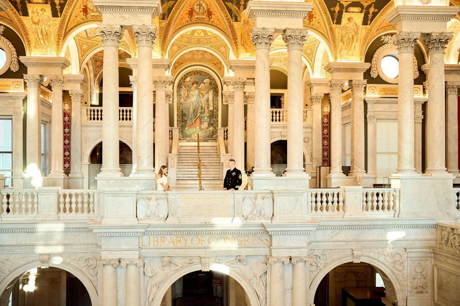 Bride and groom pose on ornate marble balcony of the Library of Congress Great Hall.