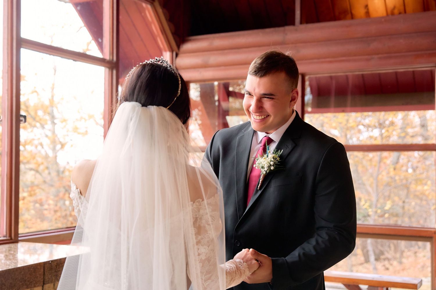 Bride and groom share an intimate moment during their autumn wedding ceremony in a rustic wooden venue.