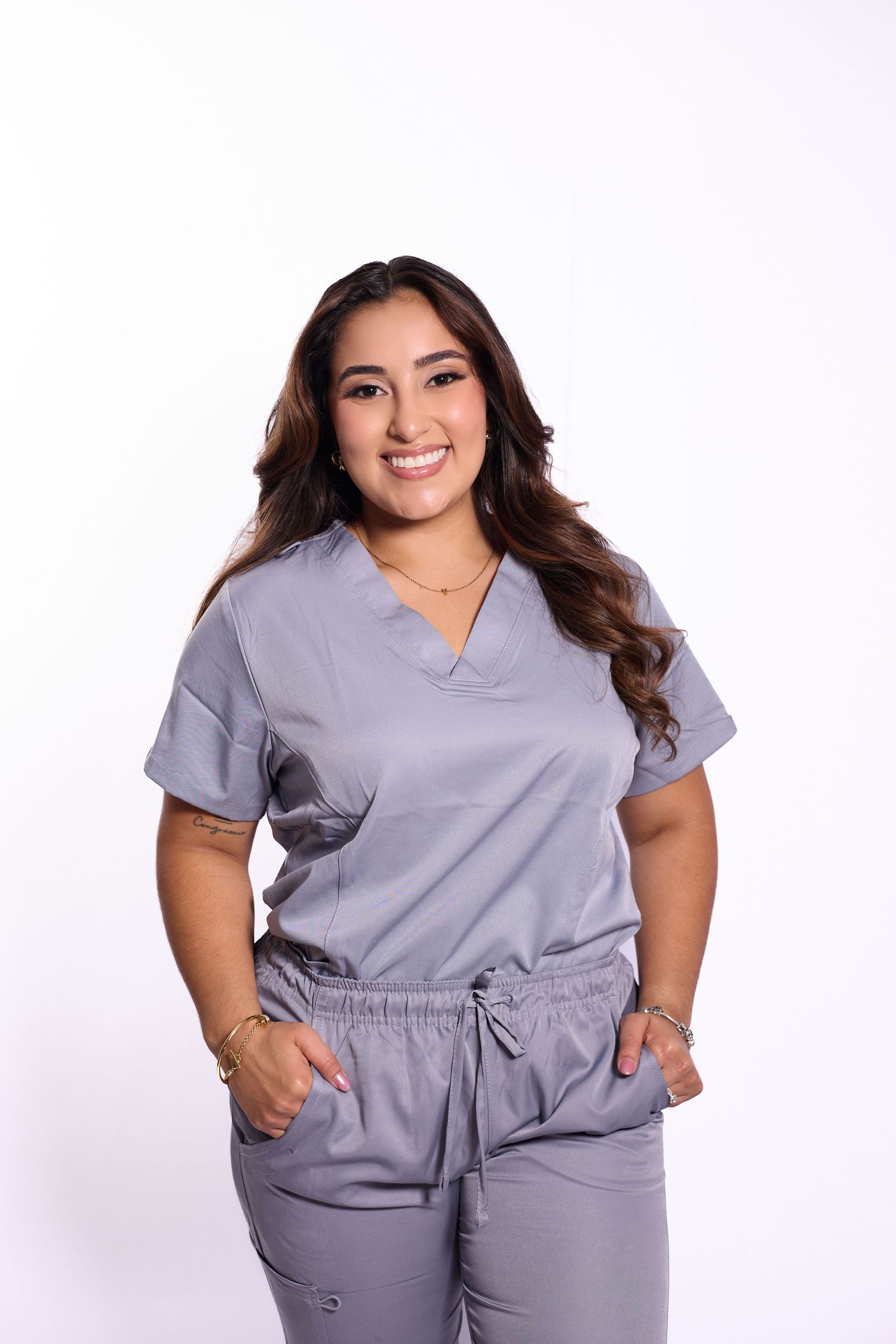 Healthcare worker poses in grey medical scrubs showing confidence and professionalism.
