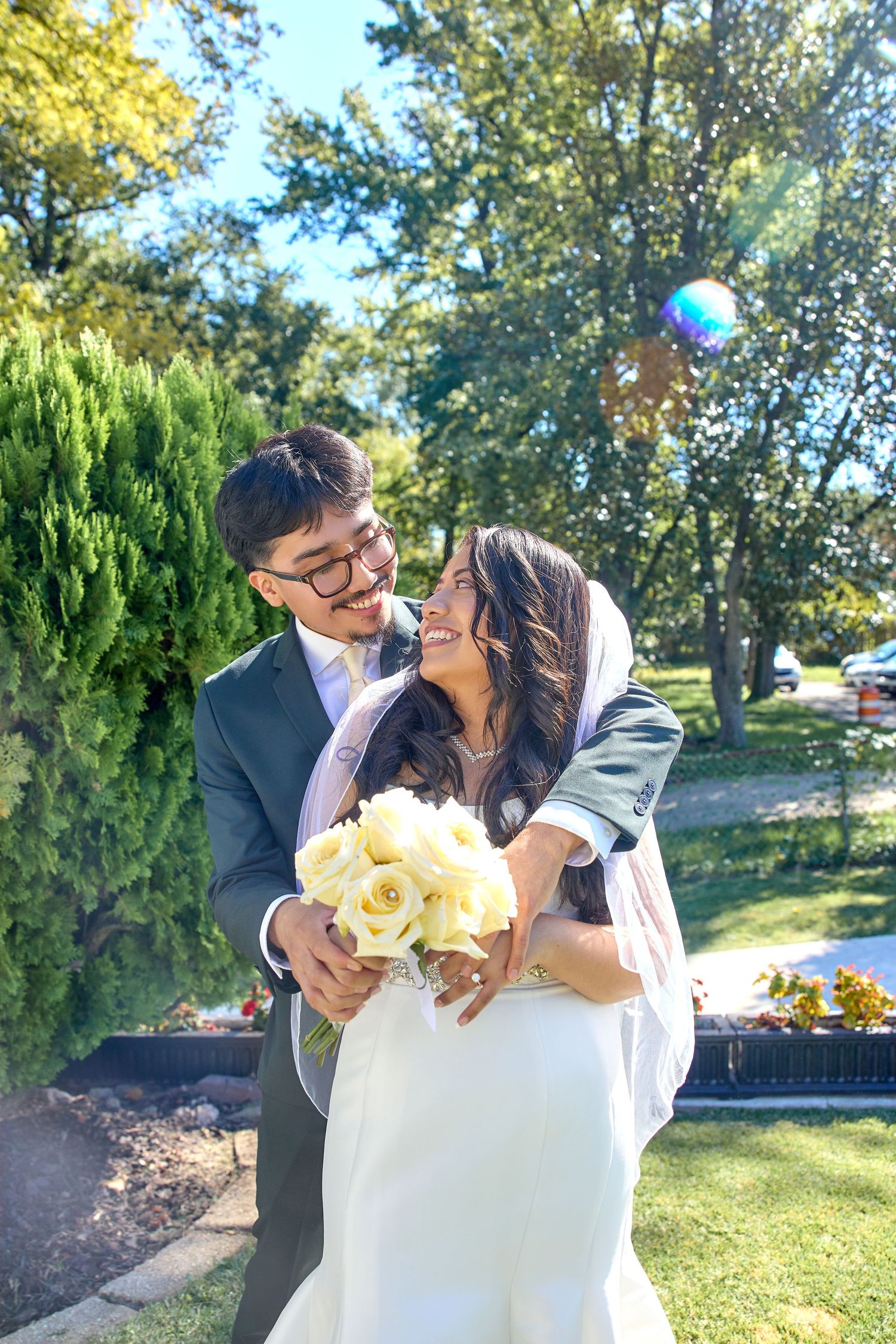 A romantic moment captured outdoors with yellow flowers and greenery in the background.