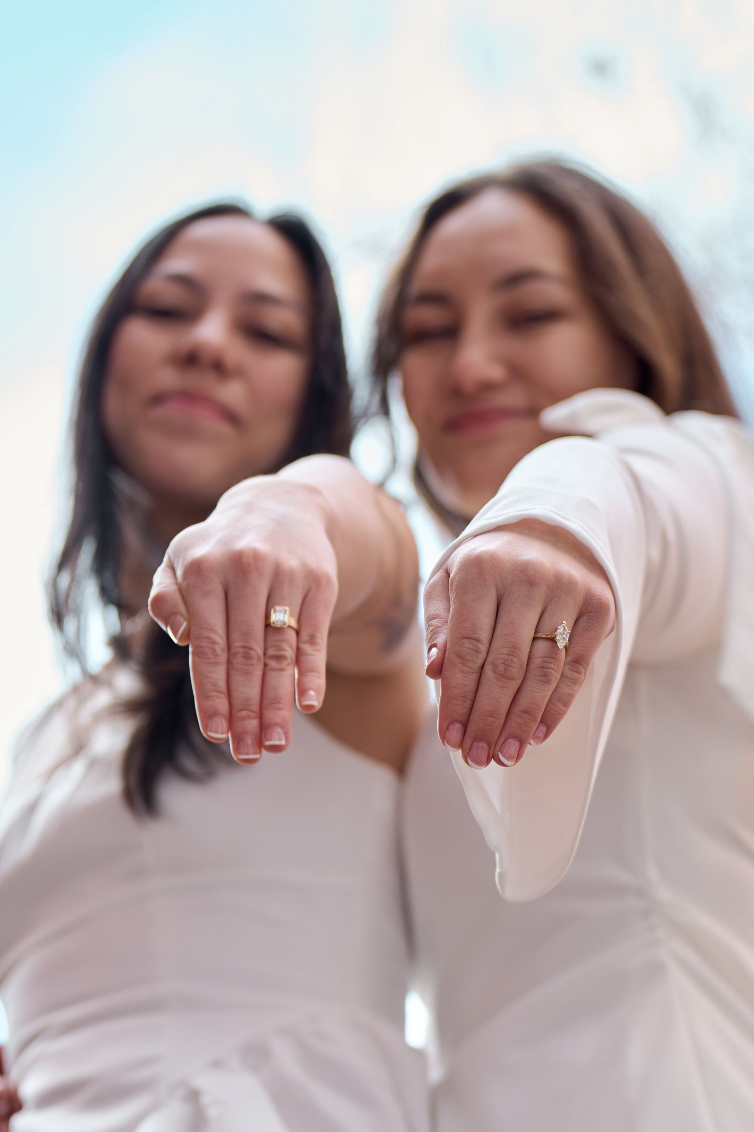 A group wearing white outfits showing their hands with engagement rings in a creative photo composition.