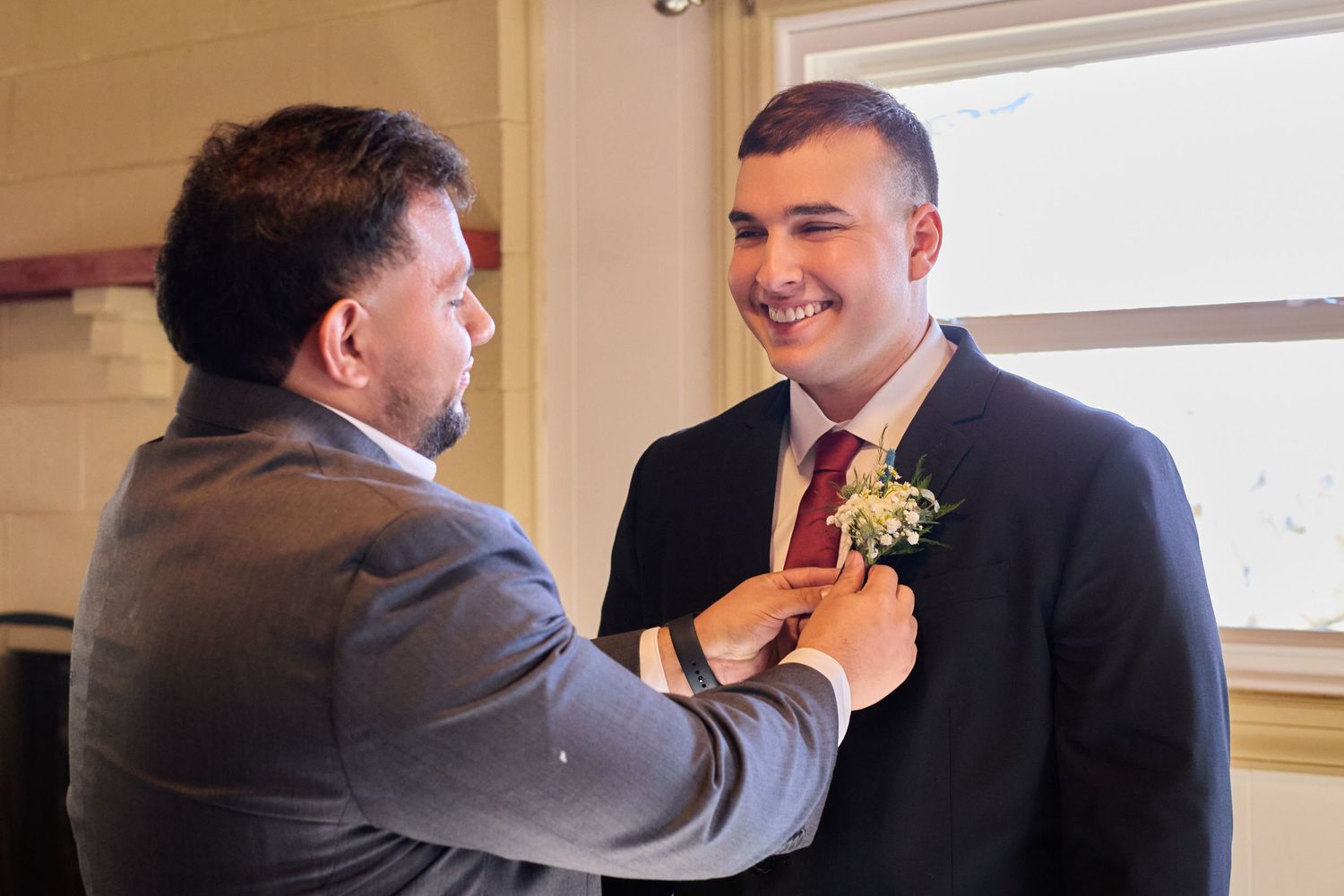 Groomsmen in dark suits share a joyful moment during wedding preparations.