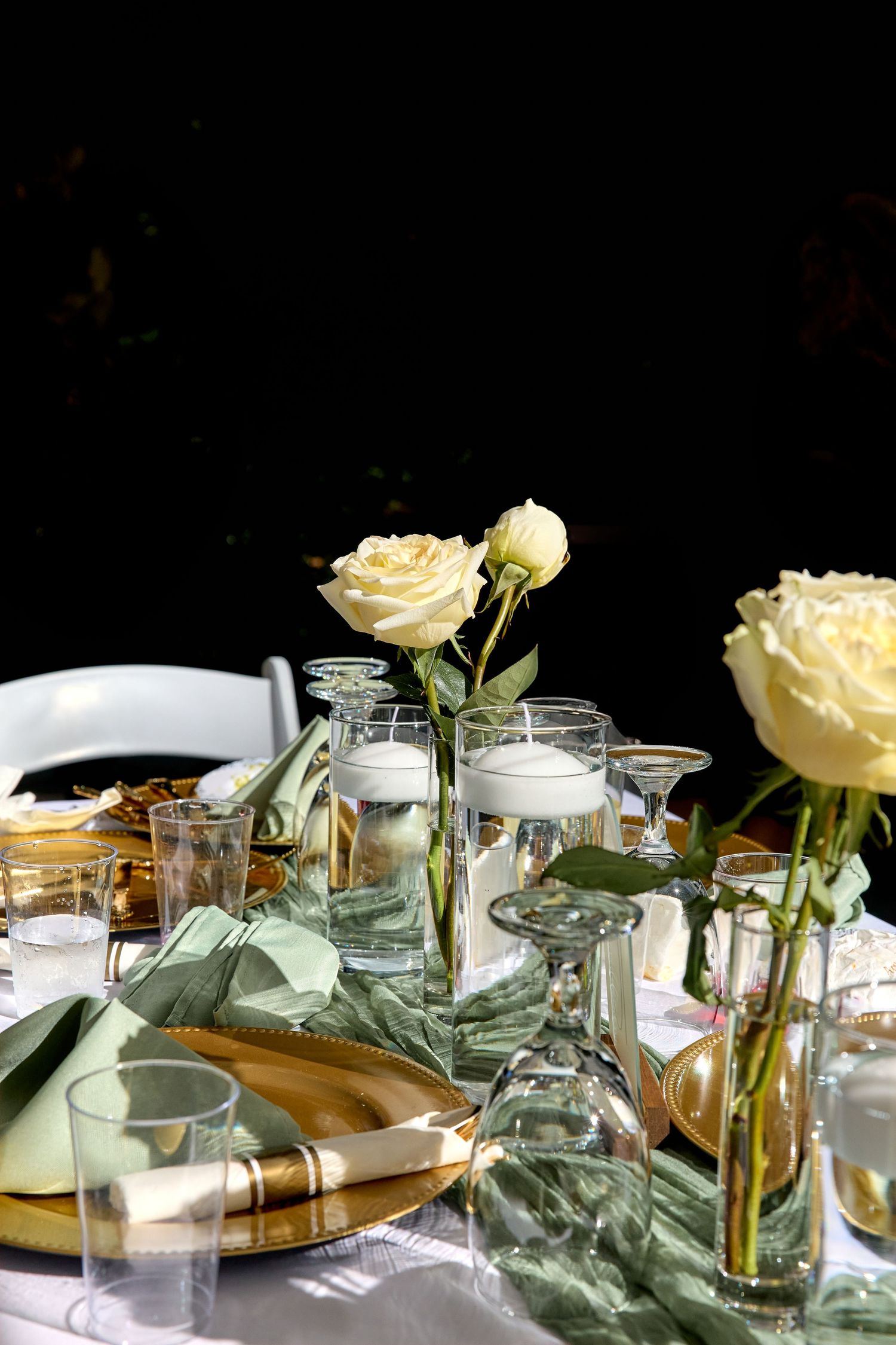 Glass vases with cream roses and eucalyptus leaves arranged on a table in soft natural lighting.