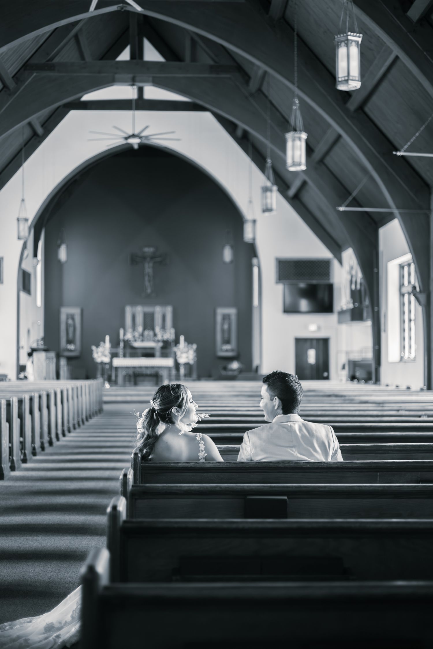 Black and white panoramic view of empty church pews and arched ceiling in a traditional sanctuary interior.