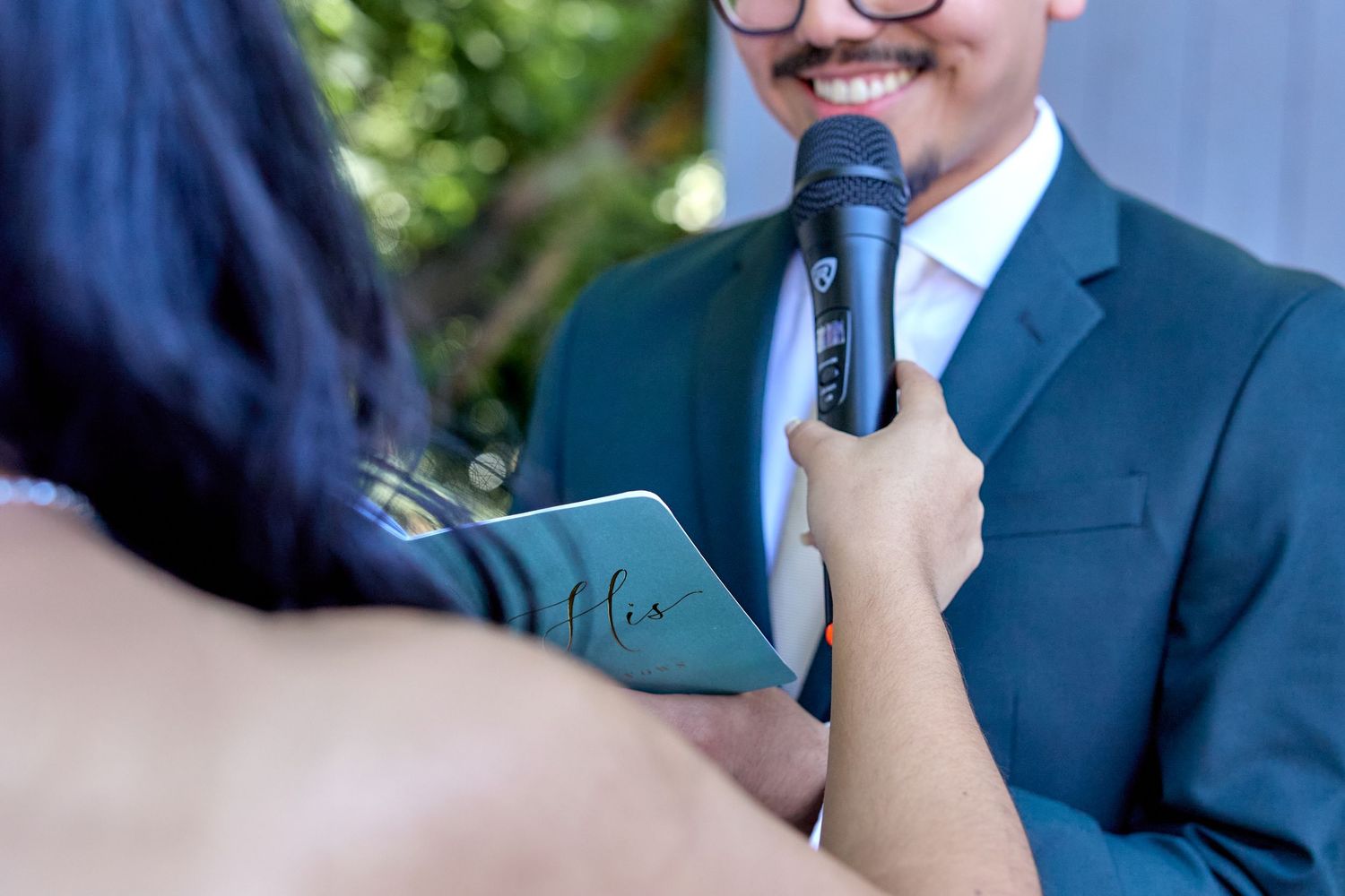 Professional speaker wearing a navy suit gestures while presenting at a business event.