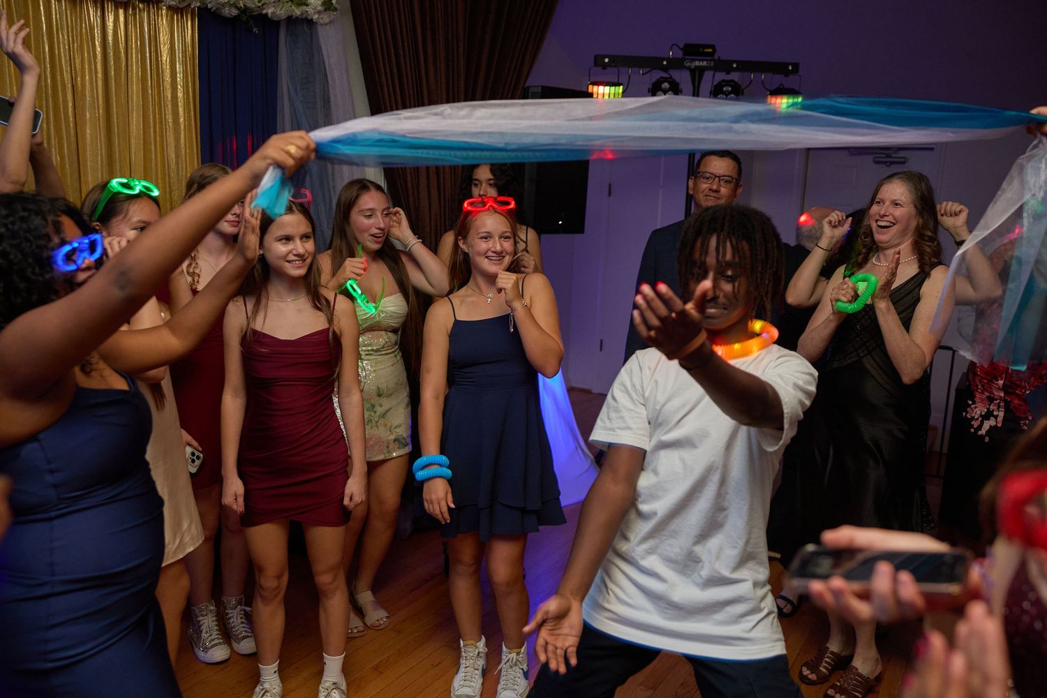People dancing and having fun at a party with colorful lighting and festive atmosphere.