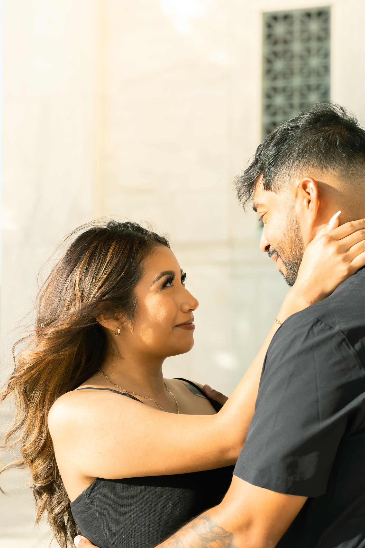 Romantic couple in black attire share intimate moments in a series of close-up shots against a light background.