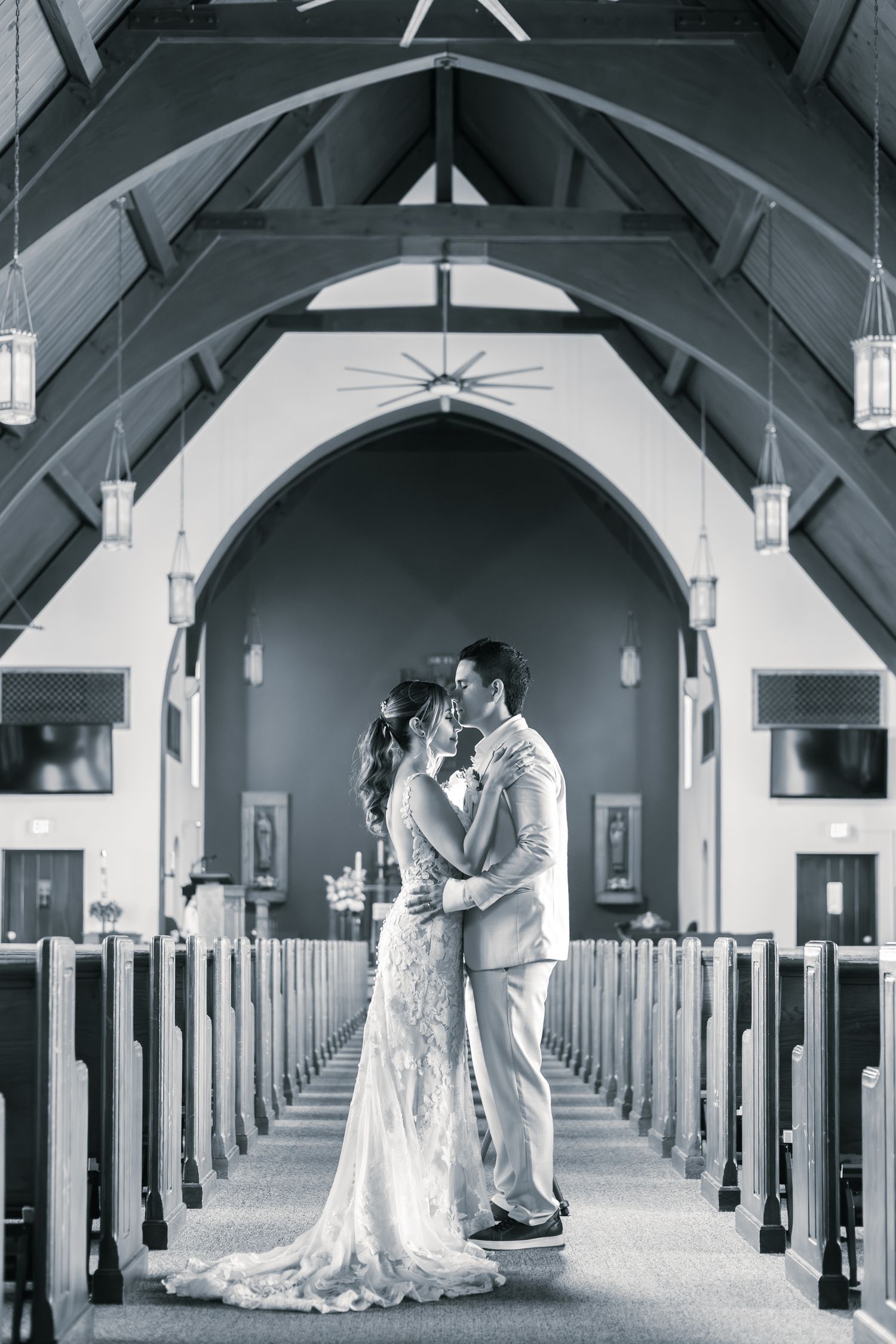 A black and white triptych photo sequence showing a couple in wedding attire embracing in a church aisle.